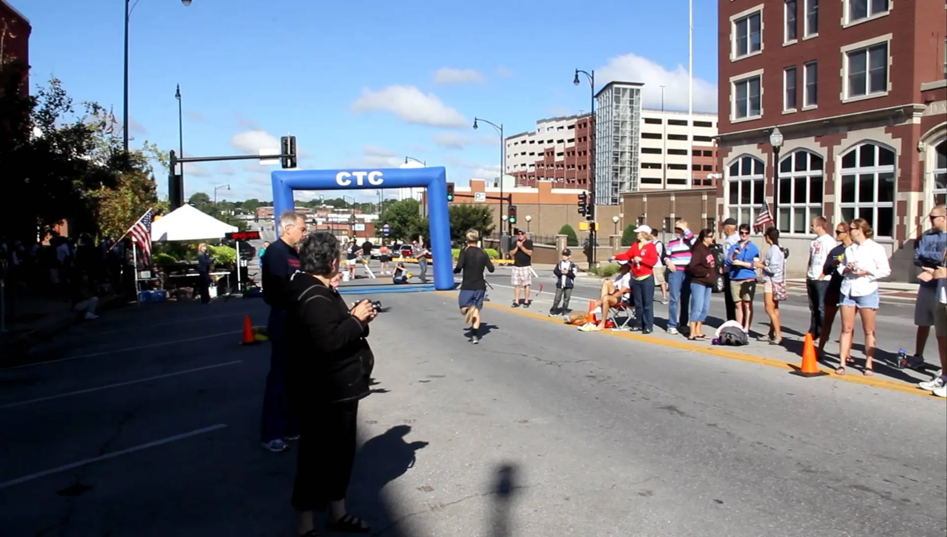 The image shows an outdoor event on a sunny day on an urban street. There