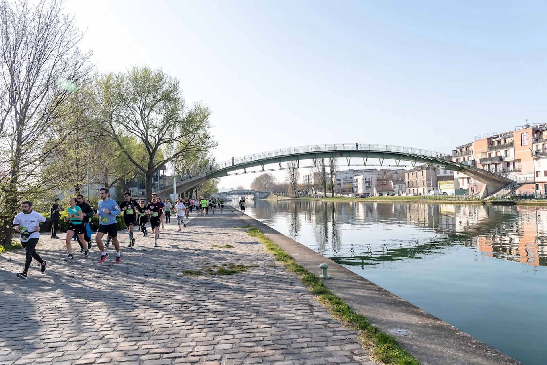 This image captures a group of people running along a paved path next to a calm