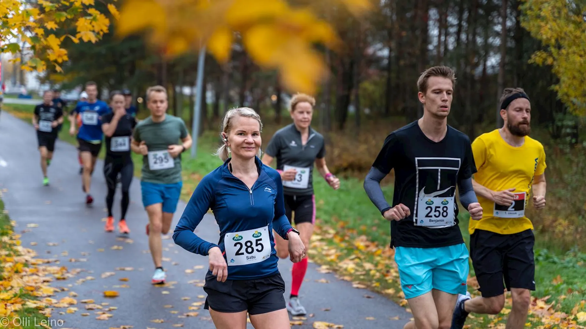 The image shows a group of runners participating in a road race. It appears to