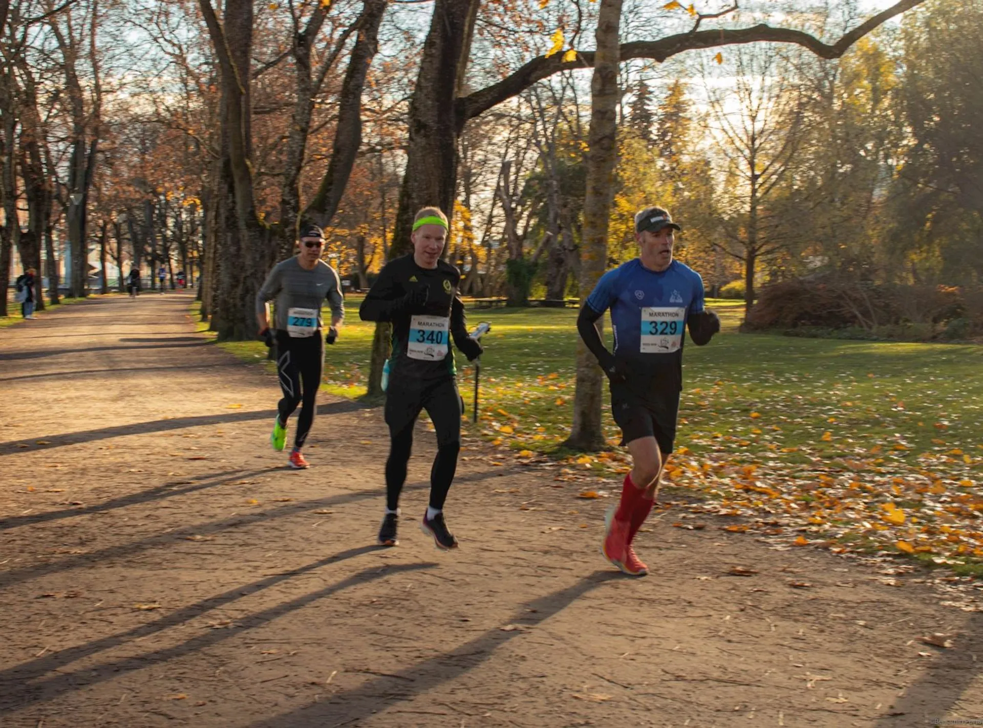 The image shows three runners participating in a race or running event. They are each