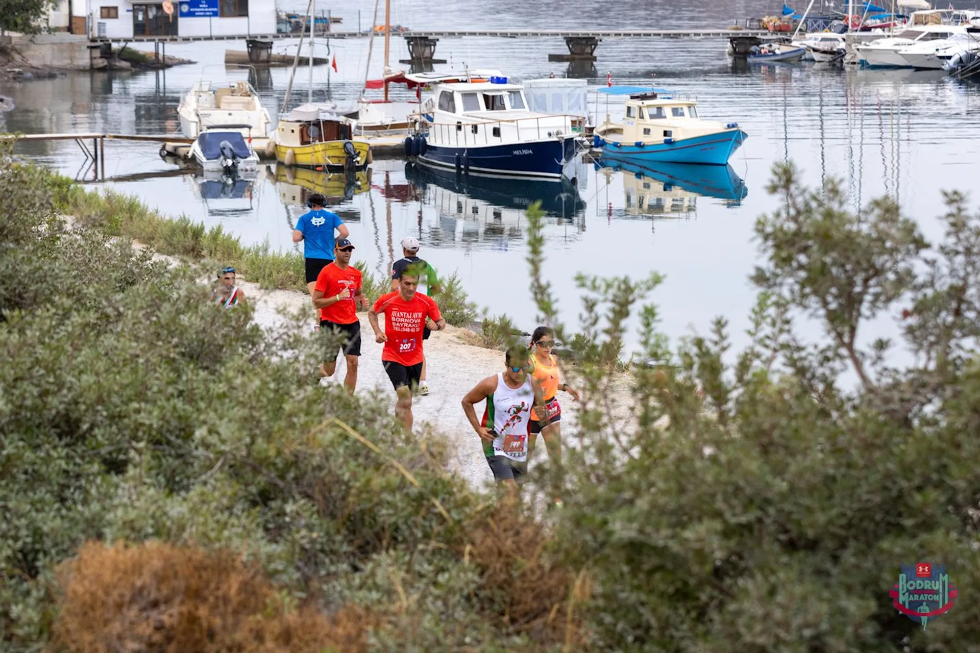 The image shows a group of runners in athletic attire on a trail with boats mo