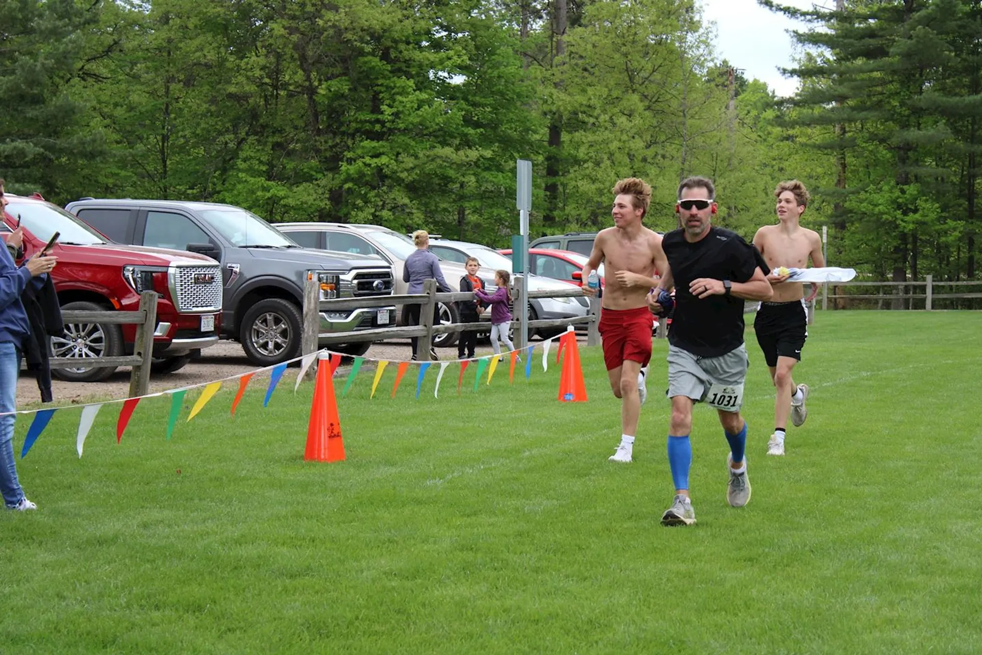 The image shows three people running in what appears to be a race or marathon.