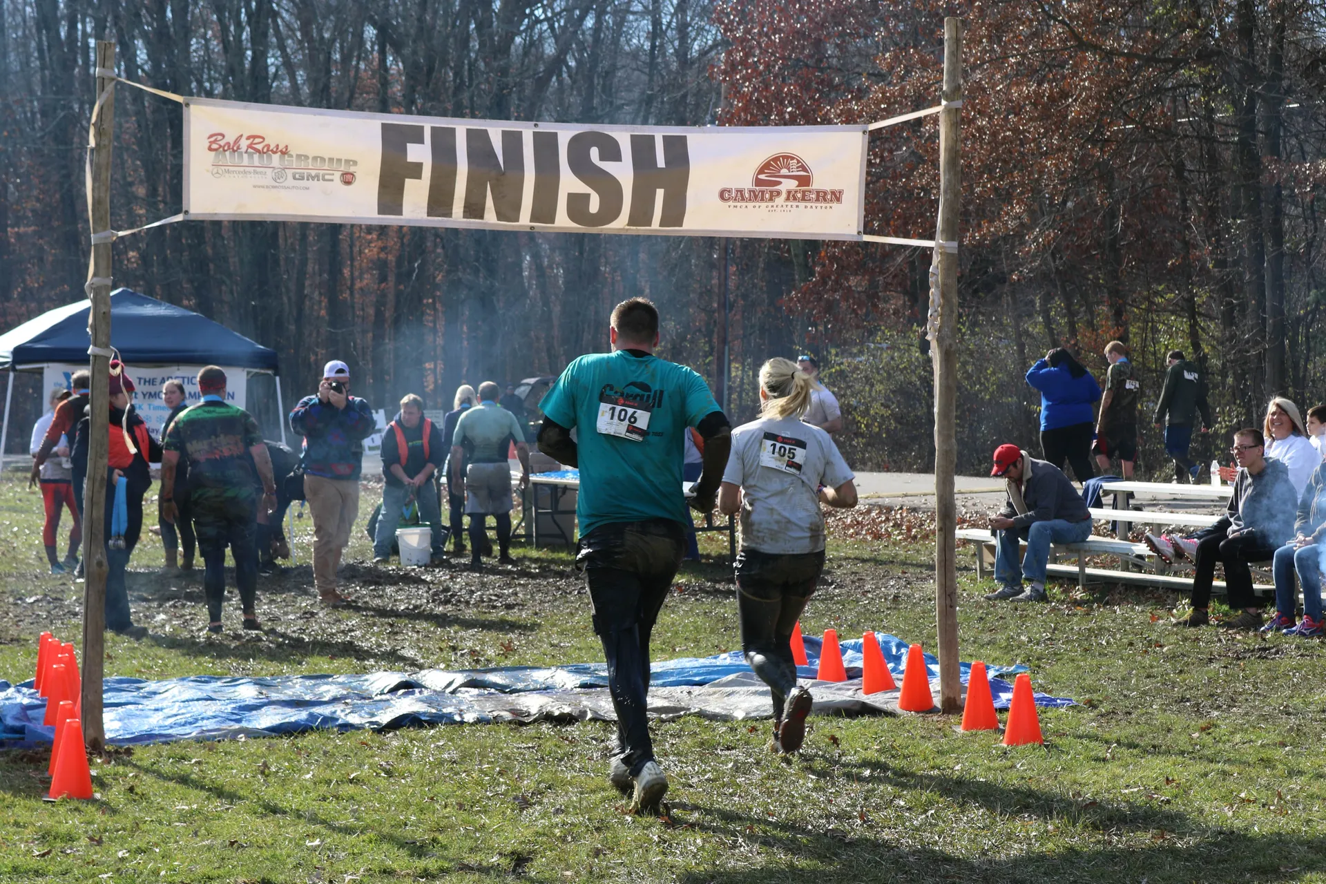 The image shows an outdoor scene at a running event where participants are crossing the finish
