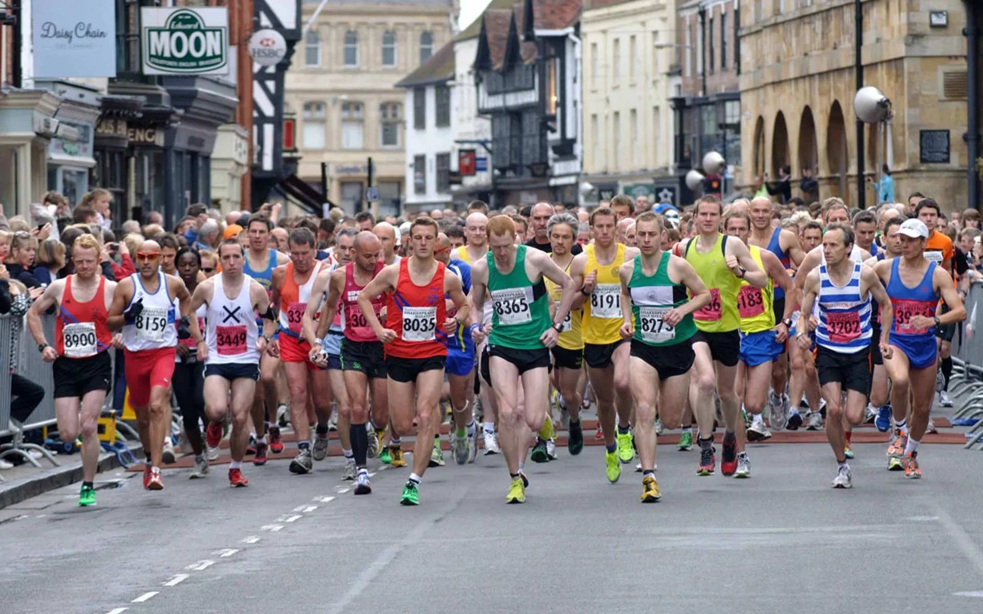 The image shows a group of runners participating in a road race. They are wearing