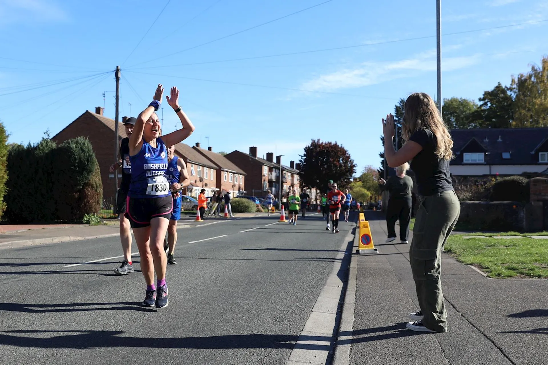 The image shows a scene from a road race, likely a marathon or half-mar