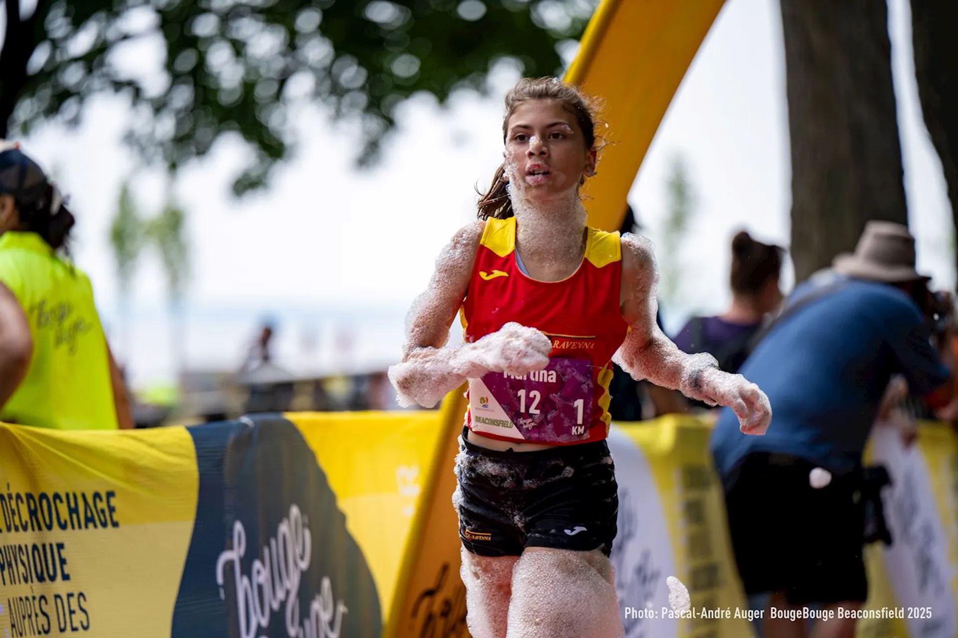 This image shows a runner participating in an event, covered with foam. It appears to be a playful or themed race. The setting seems to be outdoors, and there are barriers with event branding.