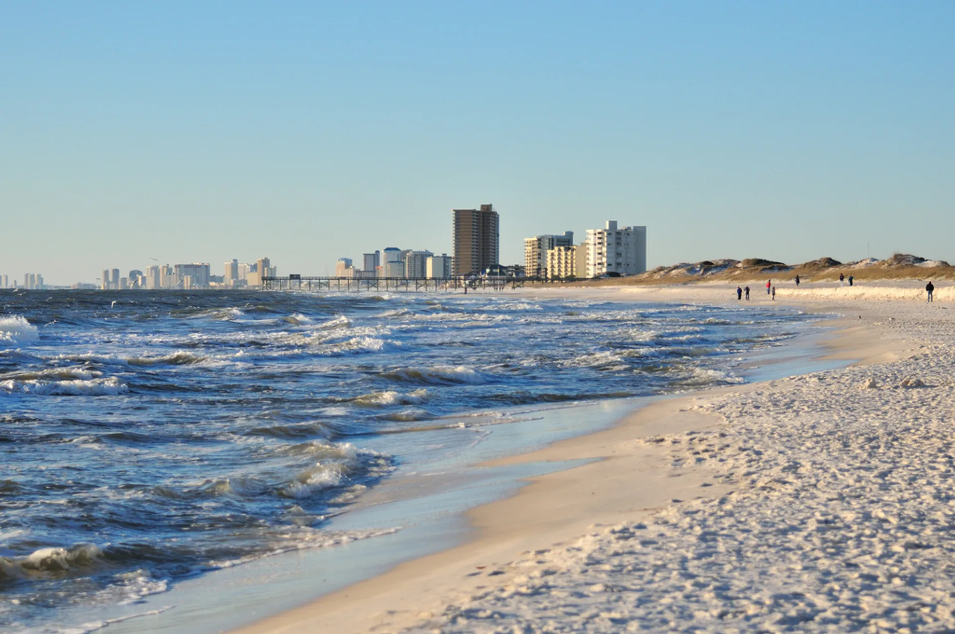 The image shows a sandy beach with waves coming in from the ocean. In the