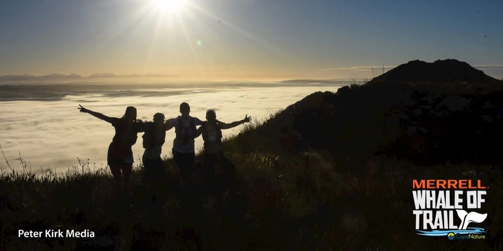 The image displays a silhouette of four individuals standing on a high vantage point with