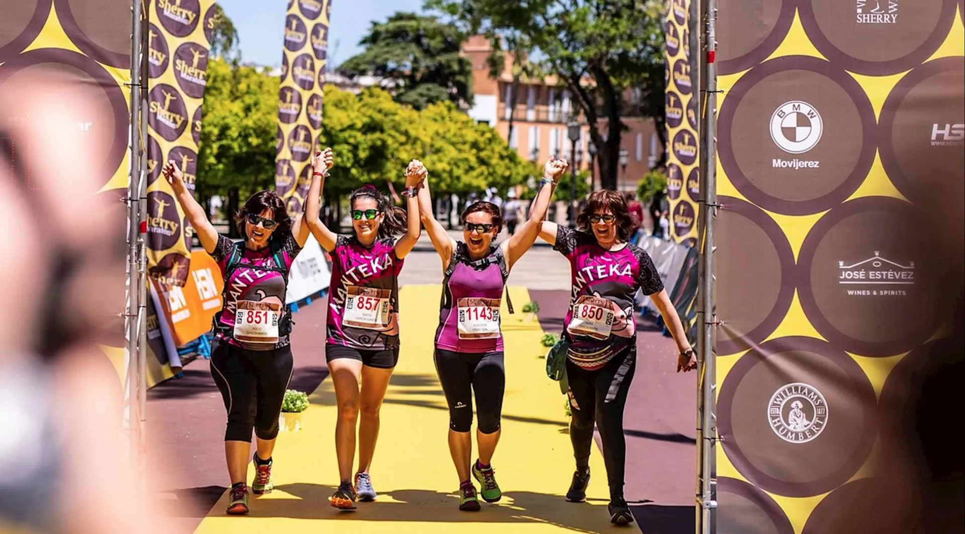 The image depicts a group of four individuals jubilantly crossing the finish line at