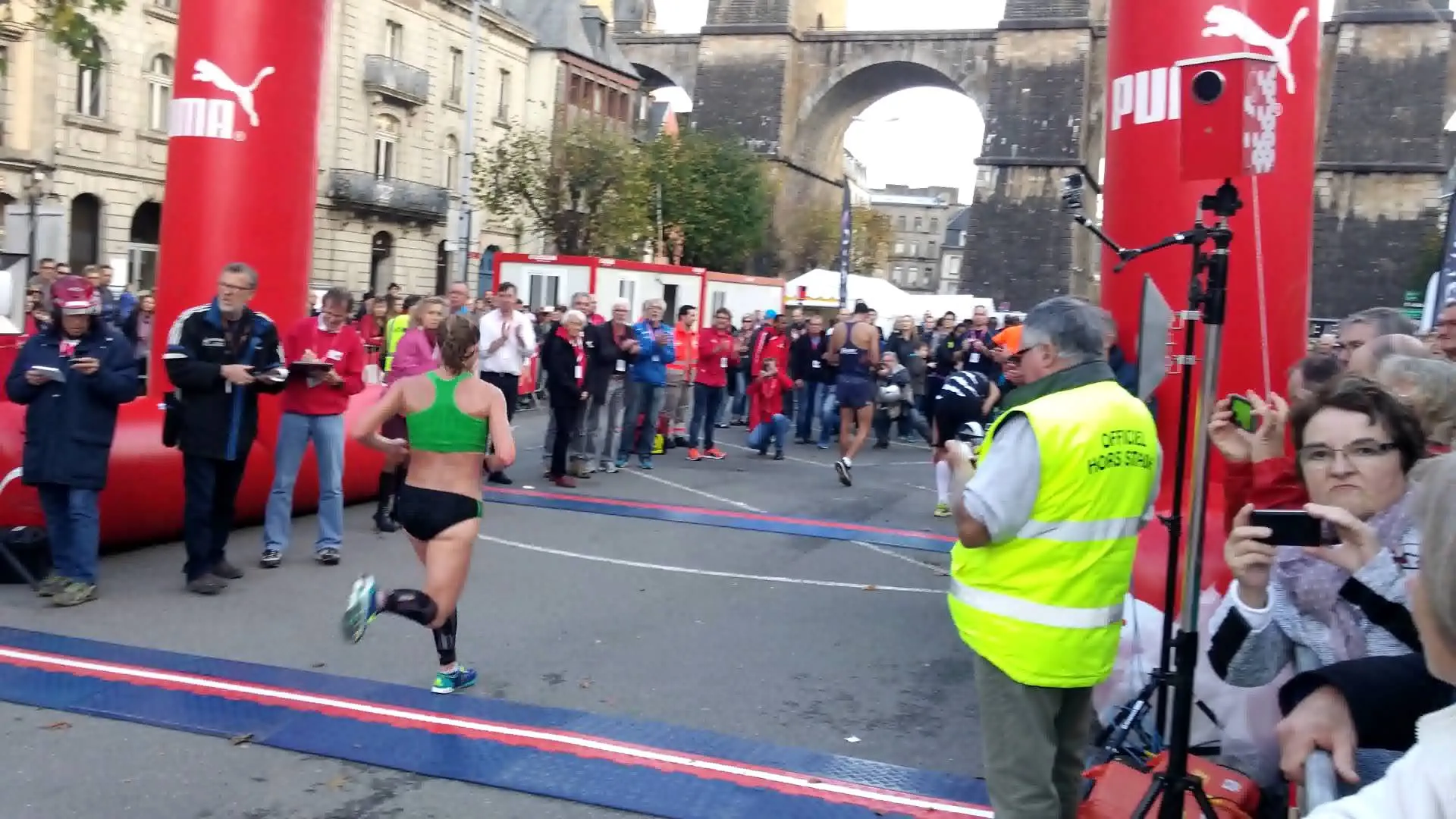 The image shows an outdoor event, likely a marathon or running race, with a