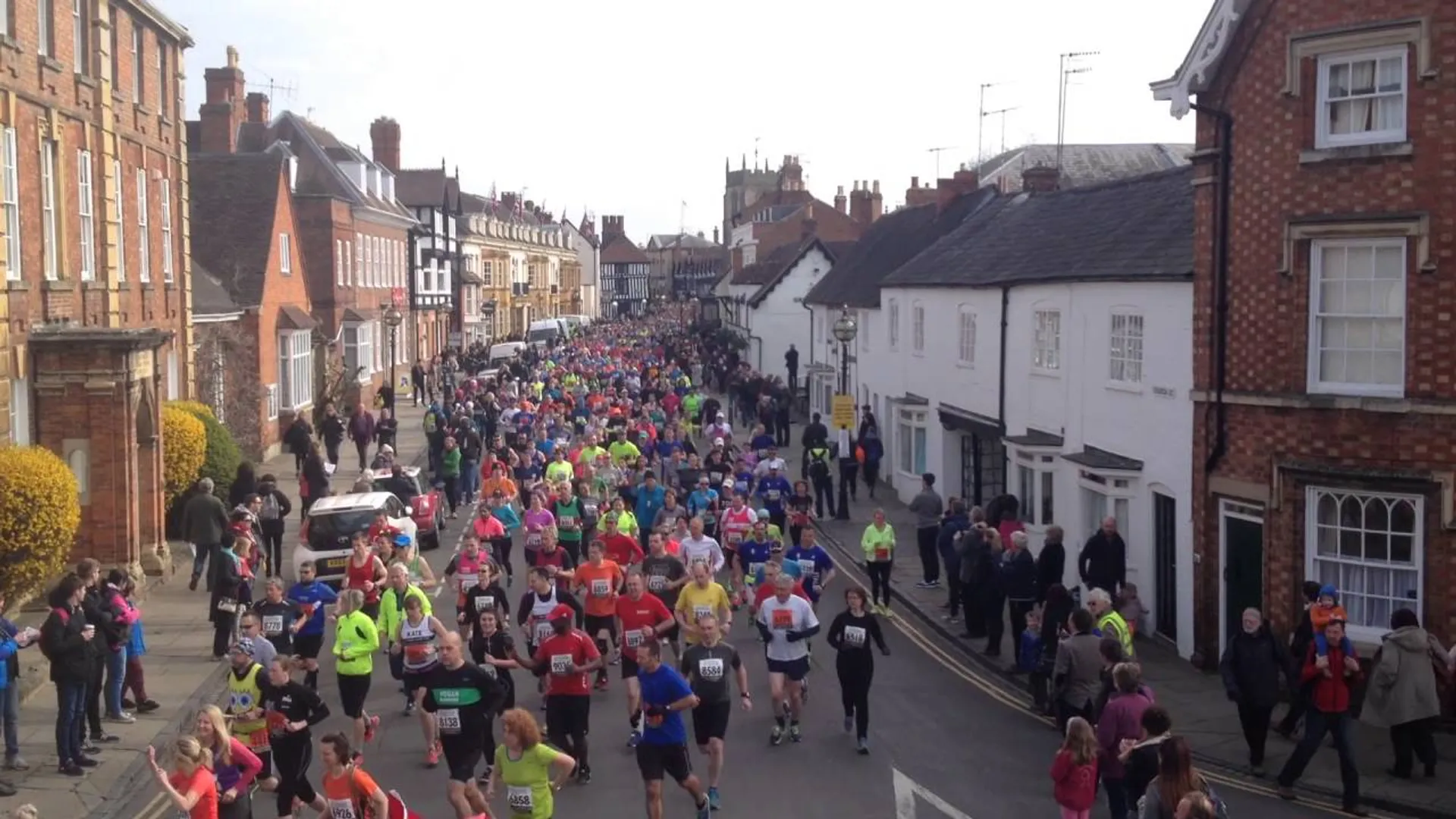 The image shows a large group of people participating in a running event, possibly a