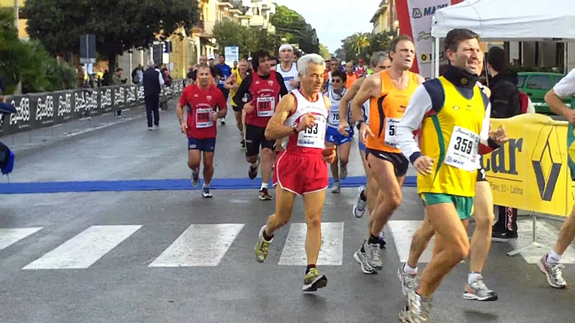 The image shows a group of runners participating in a road race. The runners are