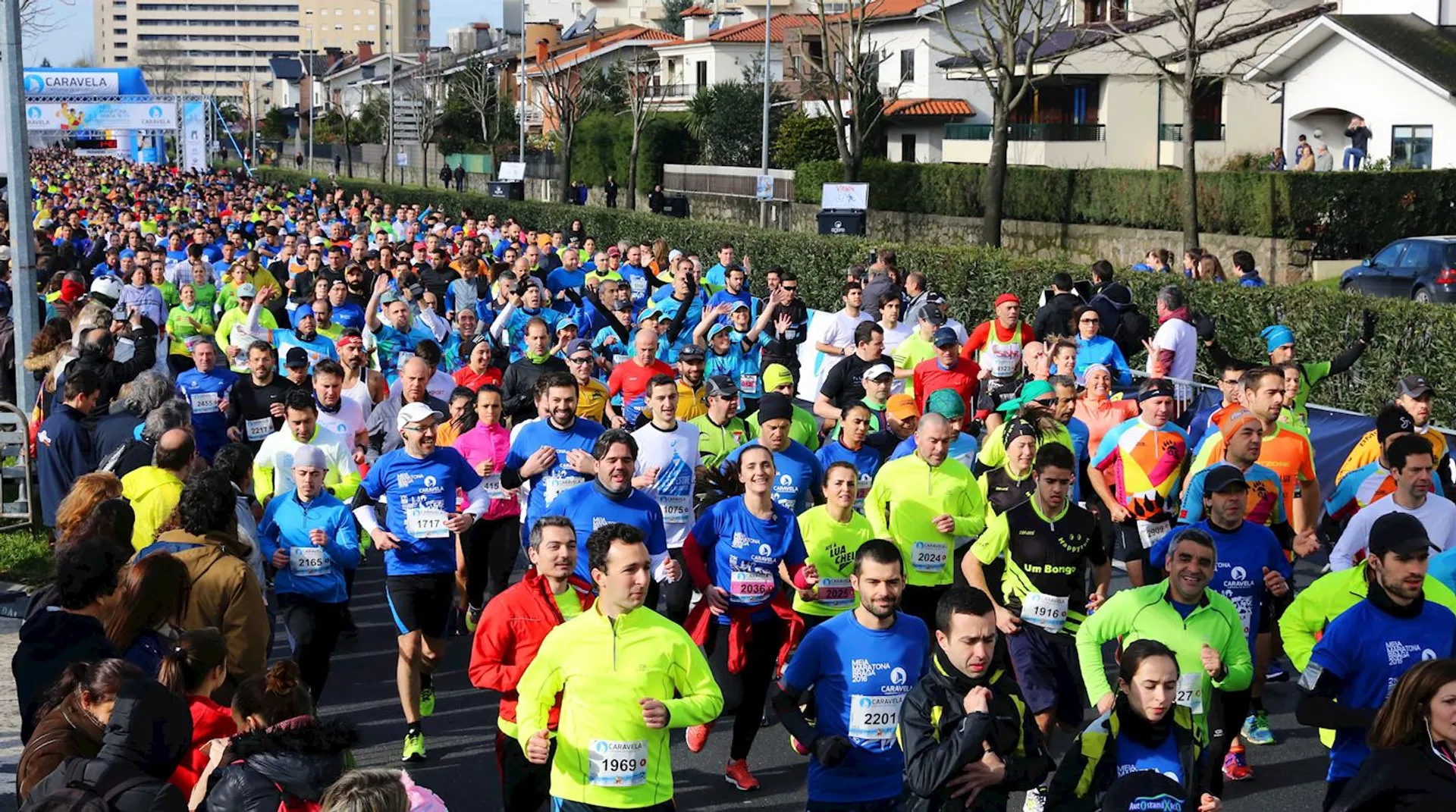 The image shows a large group of runners participating in a road race. They're
