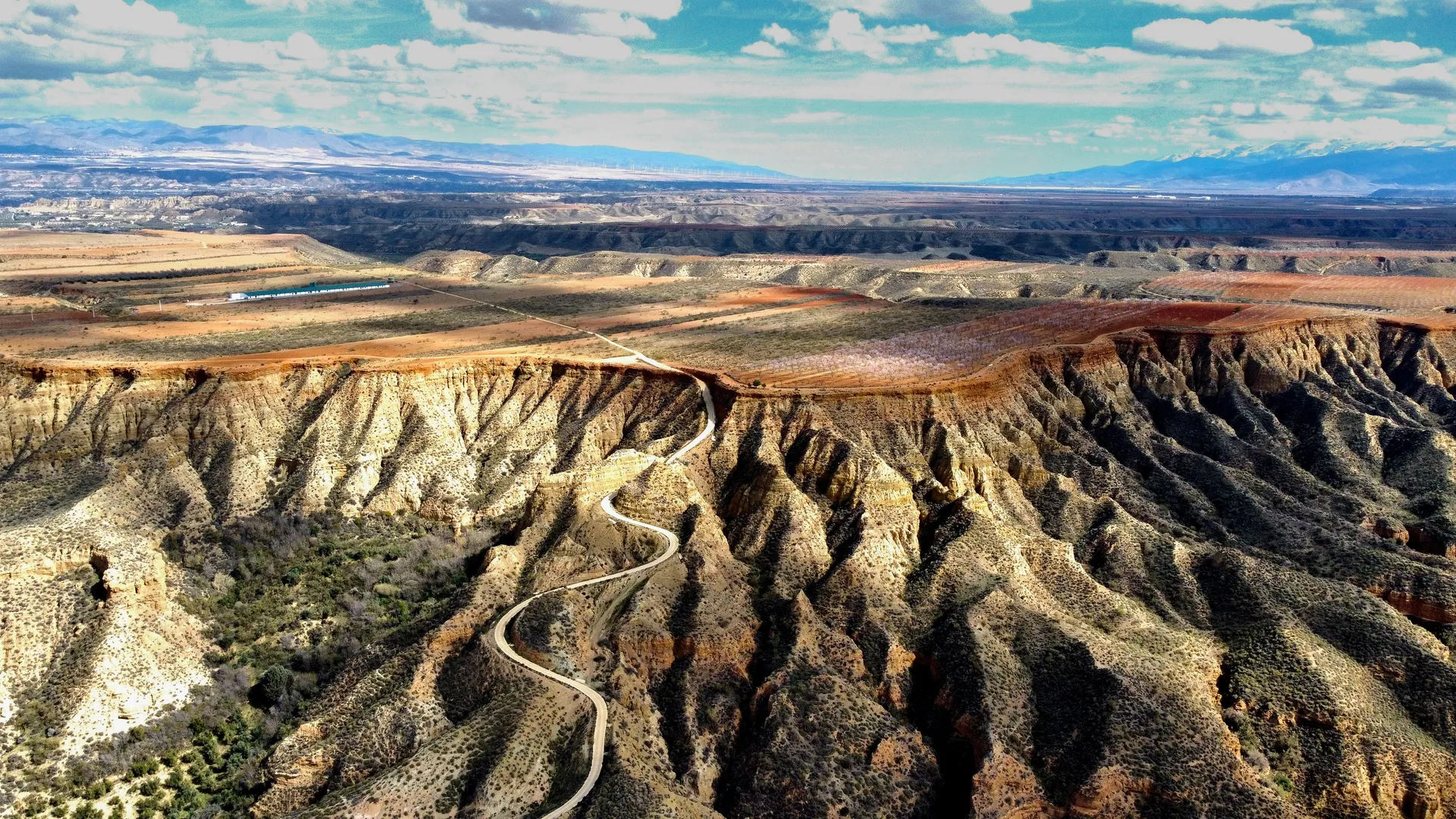 This image depicts a dramatic landscape with arid terrain featuring deep gullies and