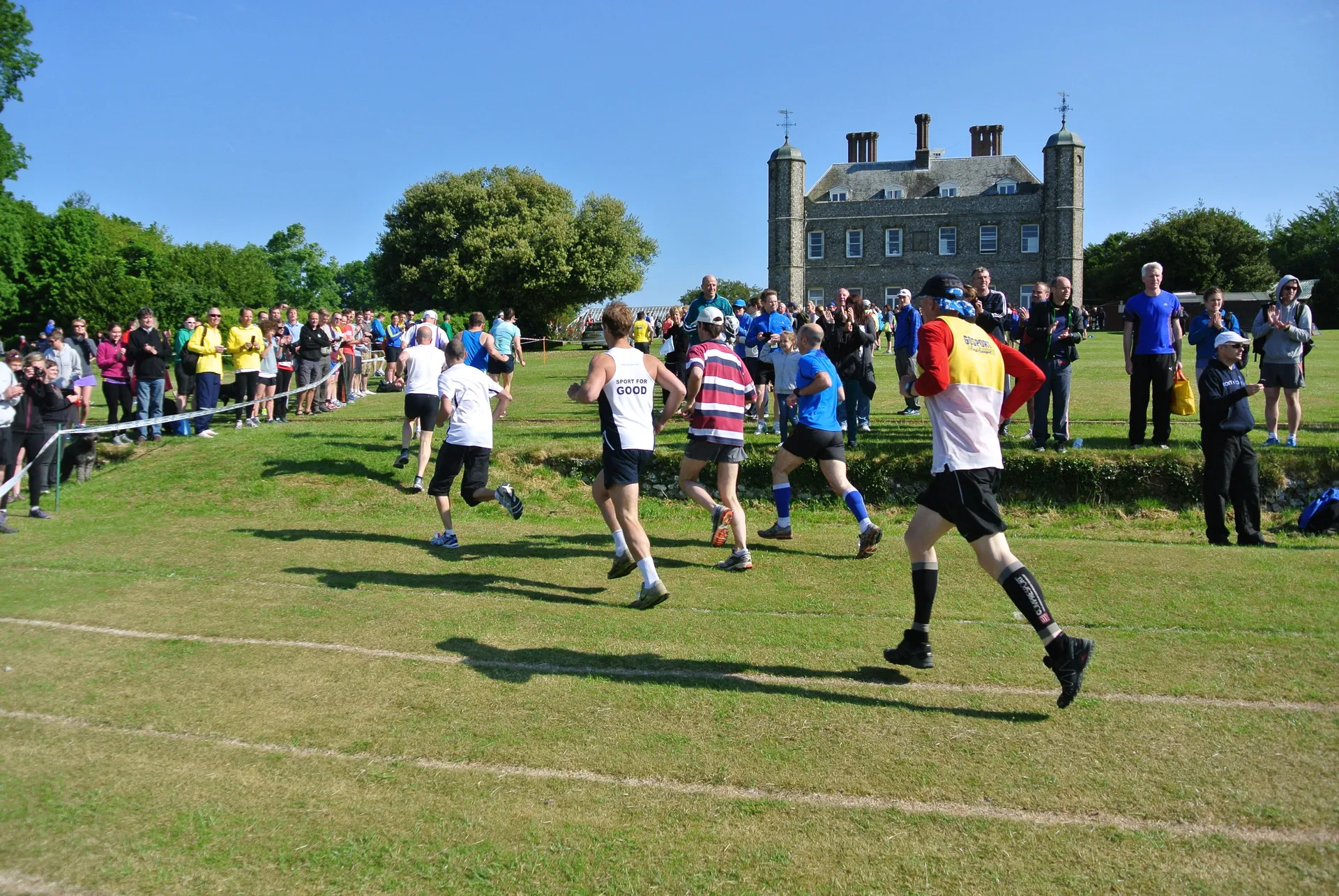 This image shows a group of people participating in an outdoor running event on a sunny