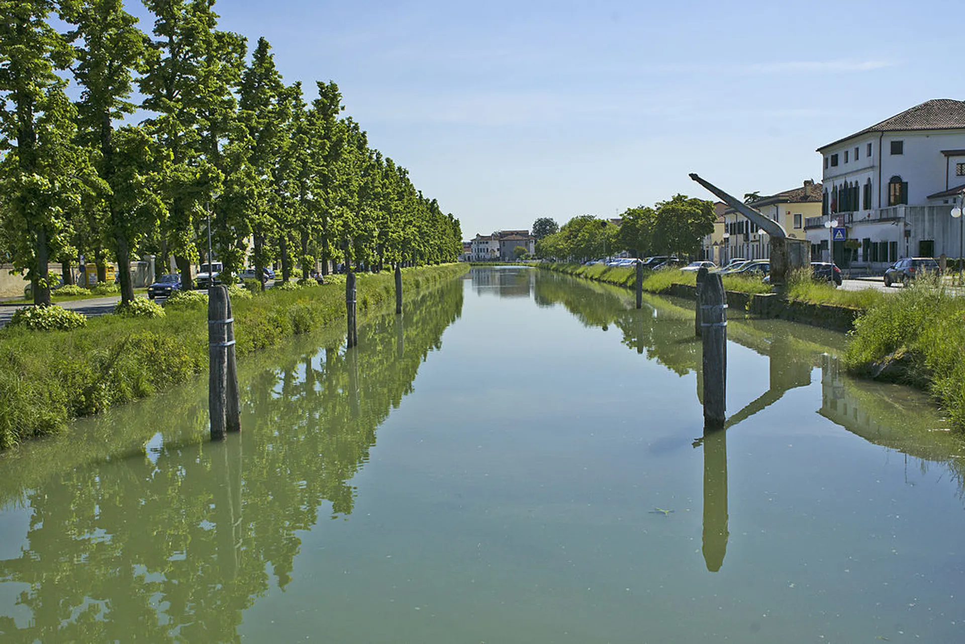 This image features a calm, wide canal or river running through a green landscape.