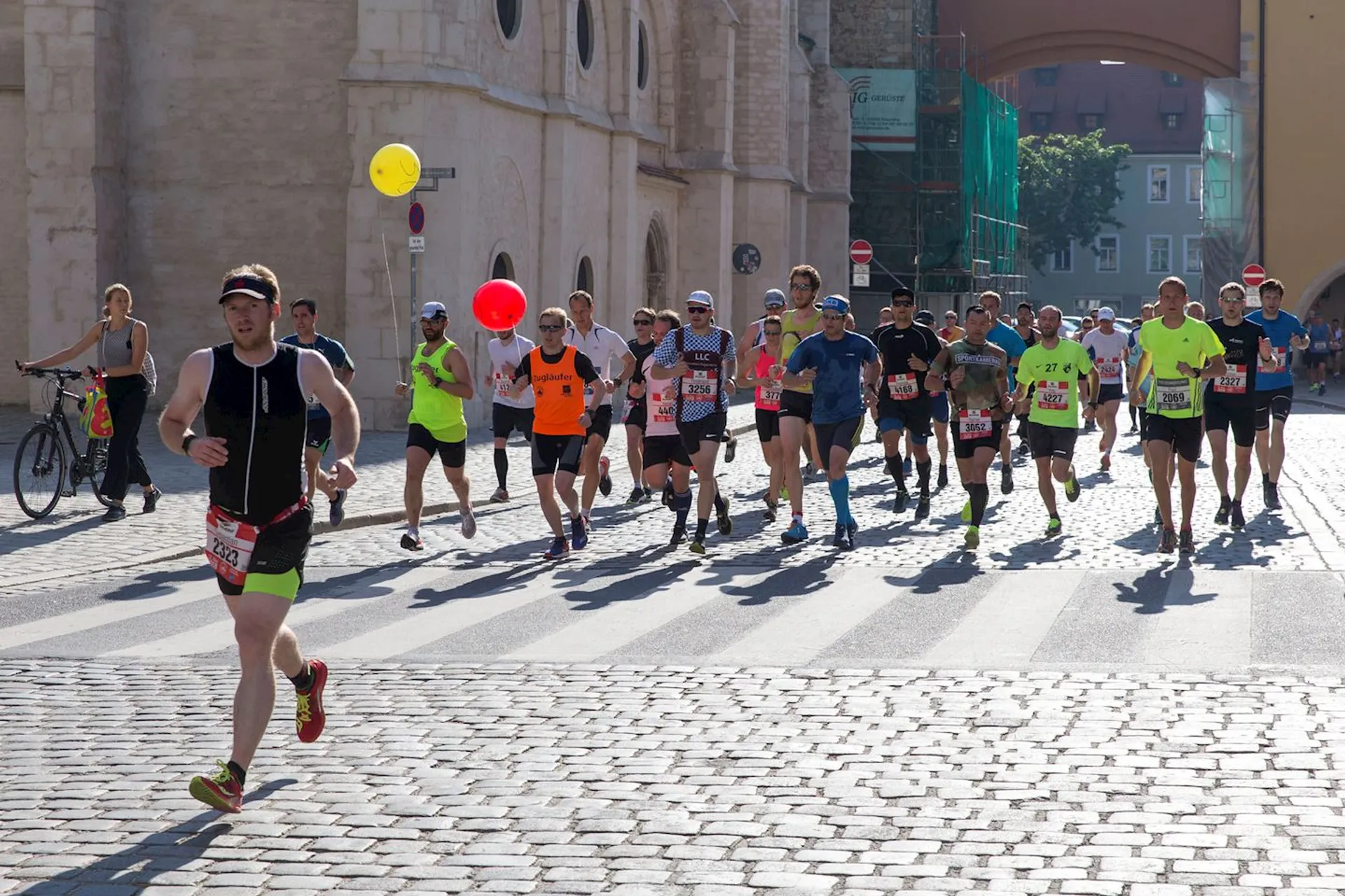 The image shows a group of runners participating in a road race. They are dressed