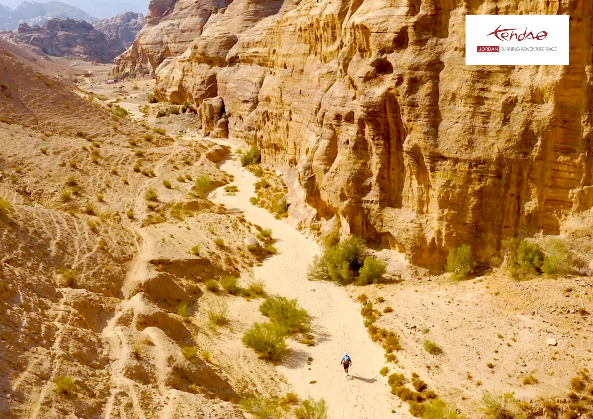 The image shows an aerial view of a dry, sandy landscape with towering rock formations