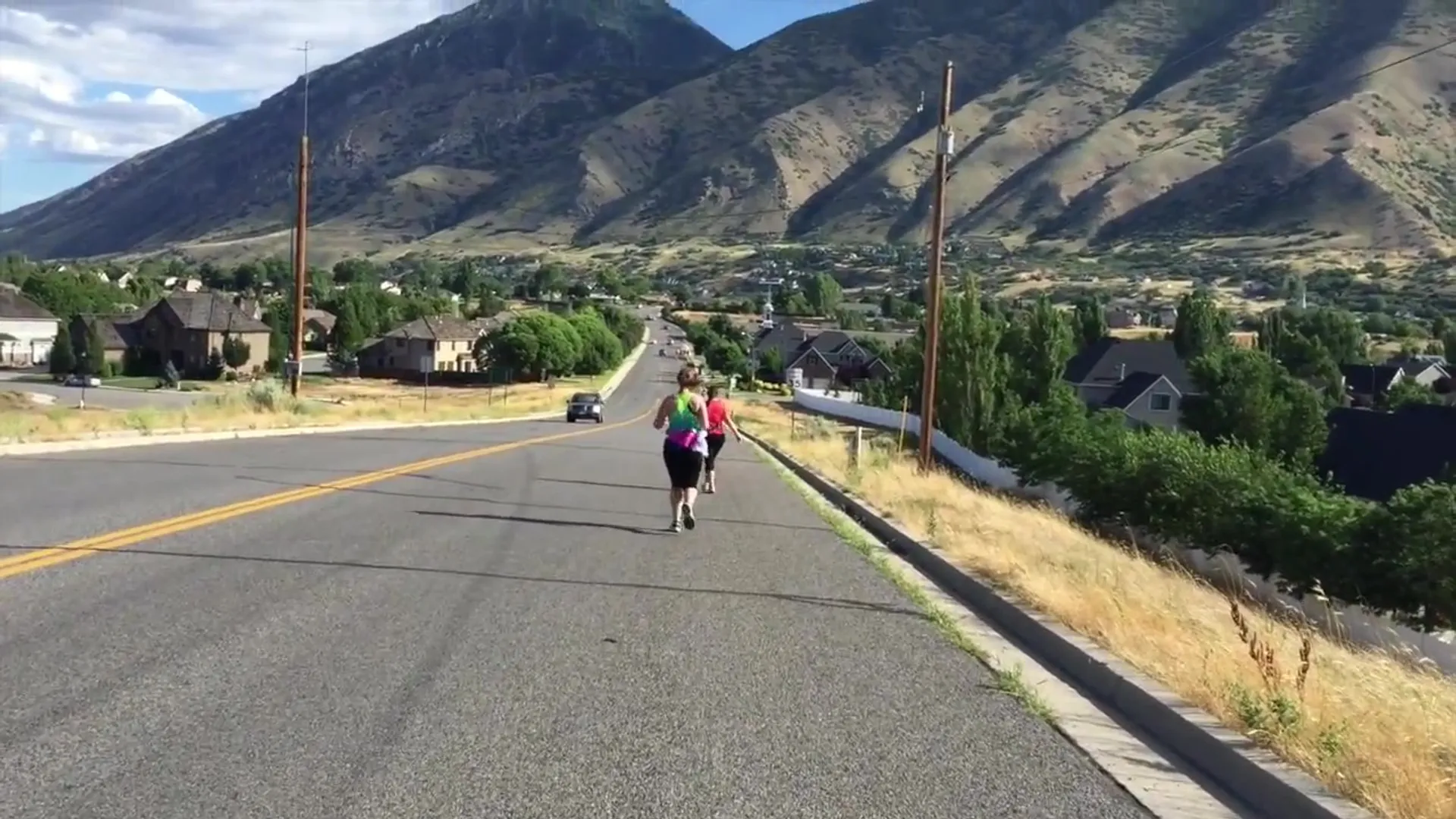 The image shows a person running down a street with houses on the side and a