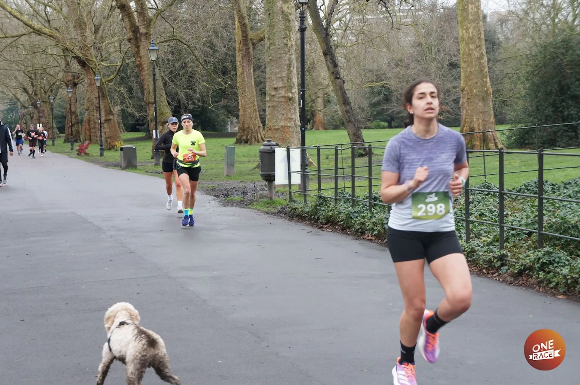 The image shows a running event taking place in a park or similar recreational area.
