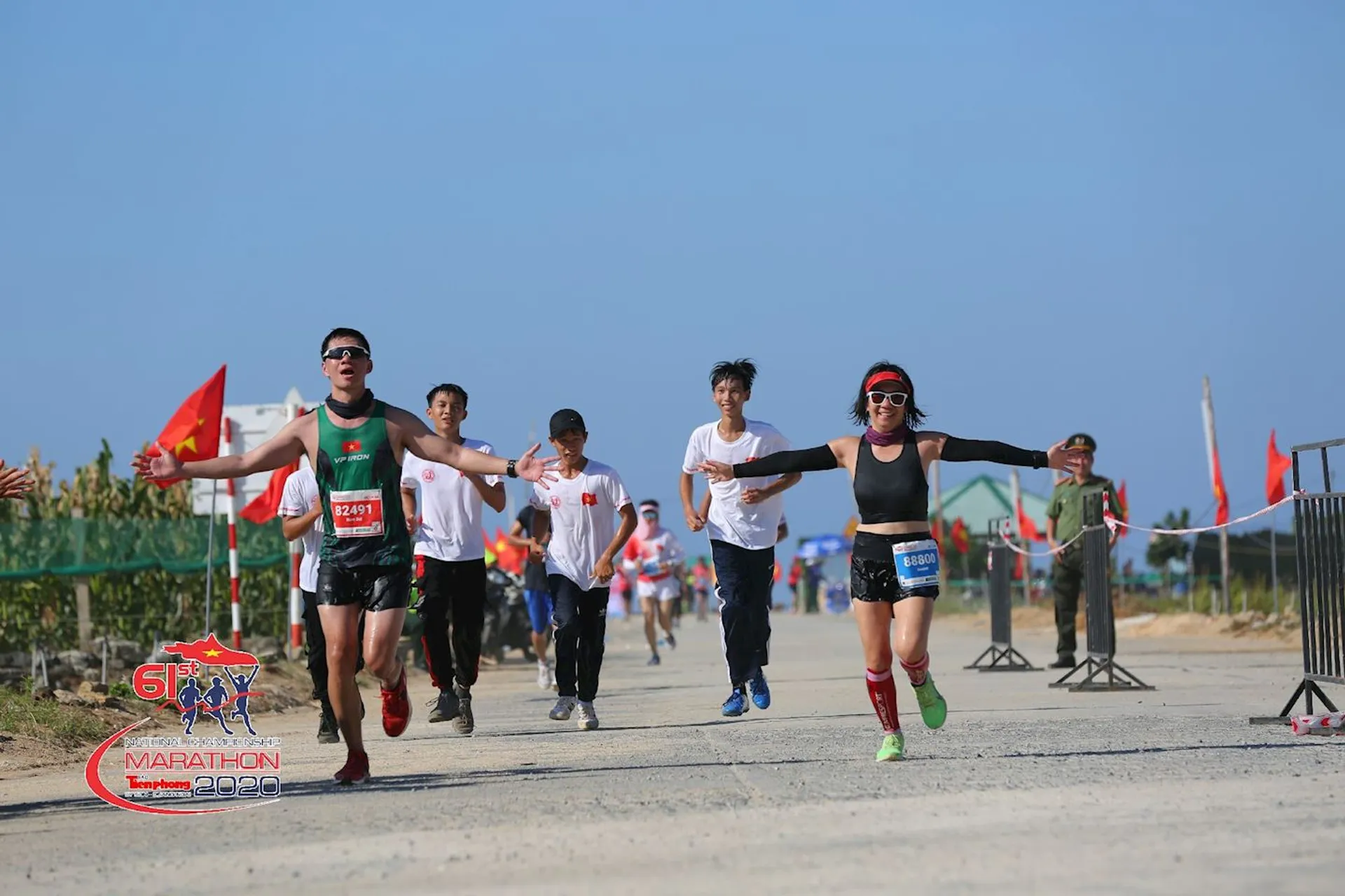 The image depicts a group of people participating in a marathon or running event. The