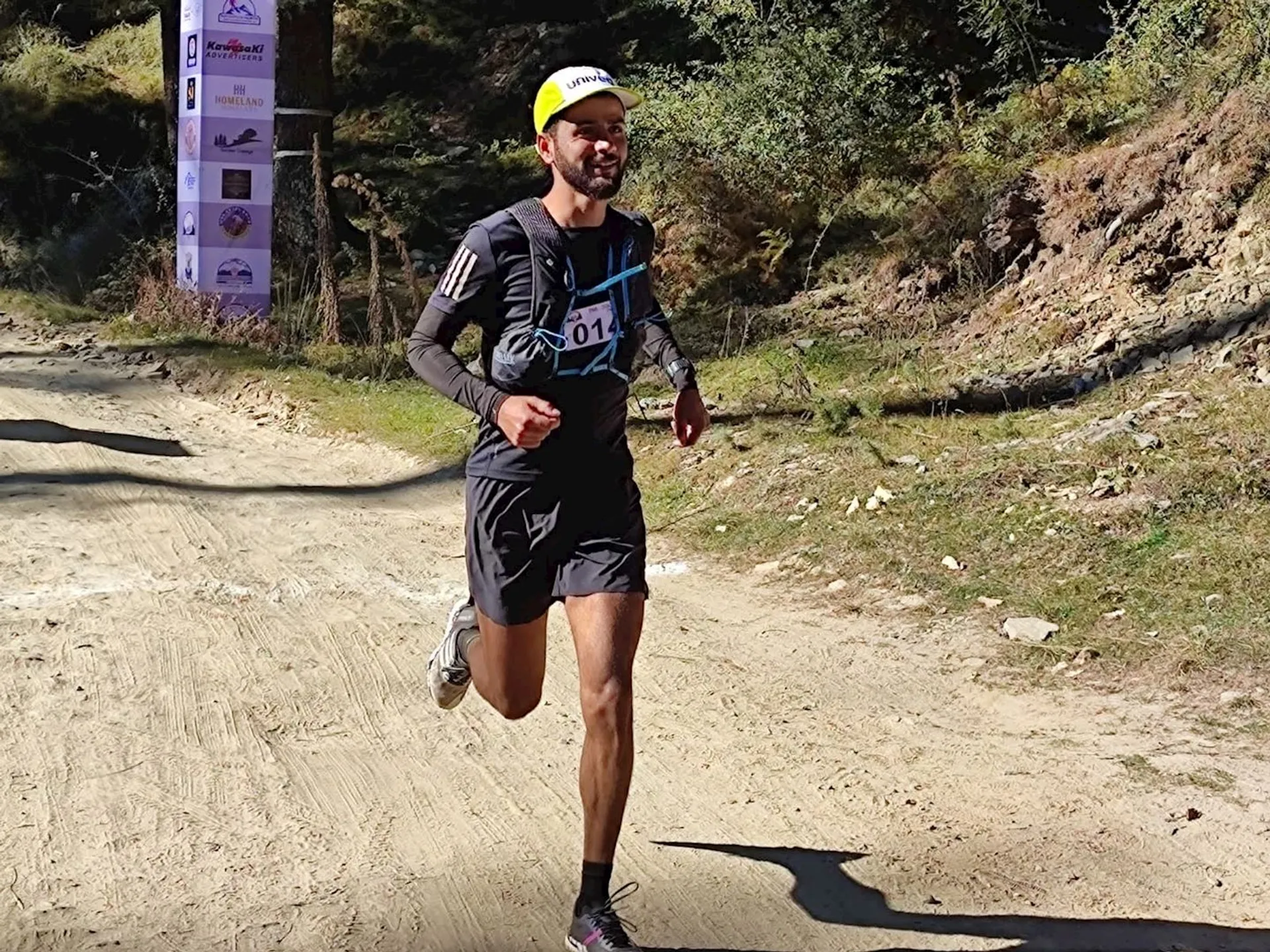 The image shows a male runner in motion, competing in a trail running event.