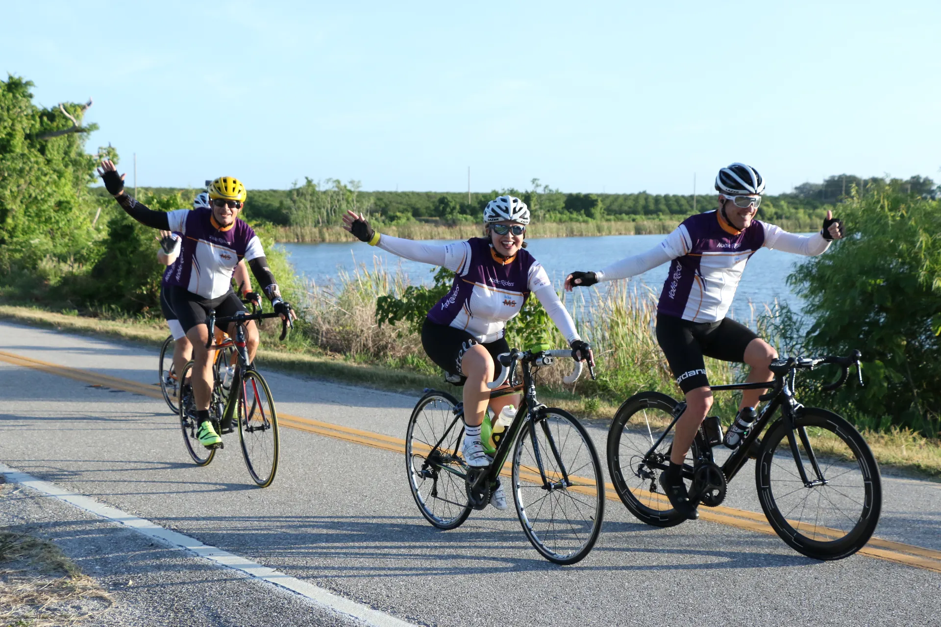 The image shows three cyclists riding on a road. They appear to be in a