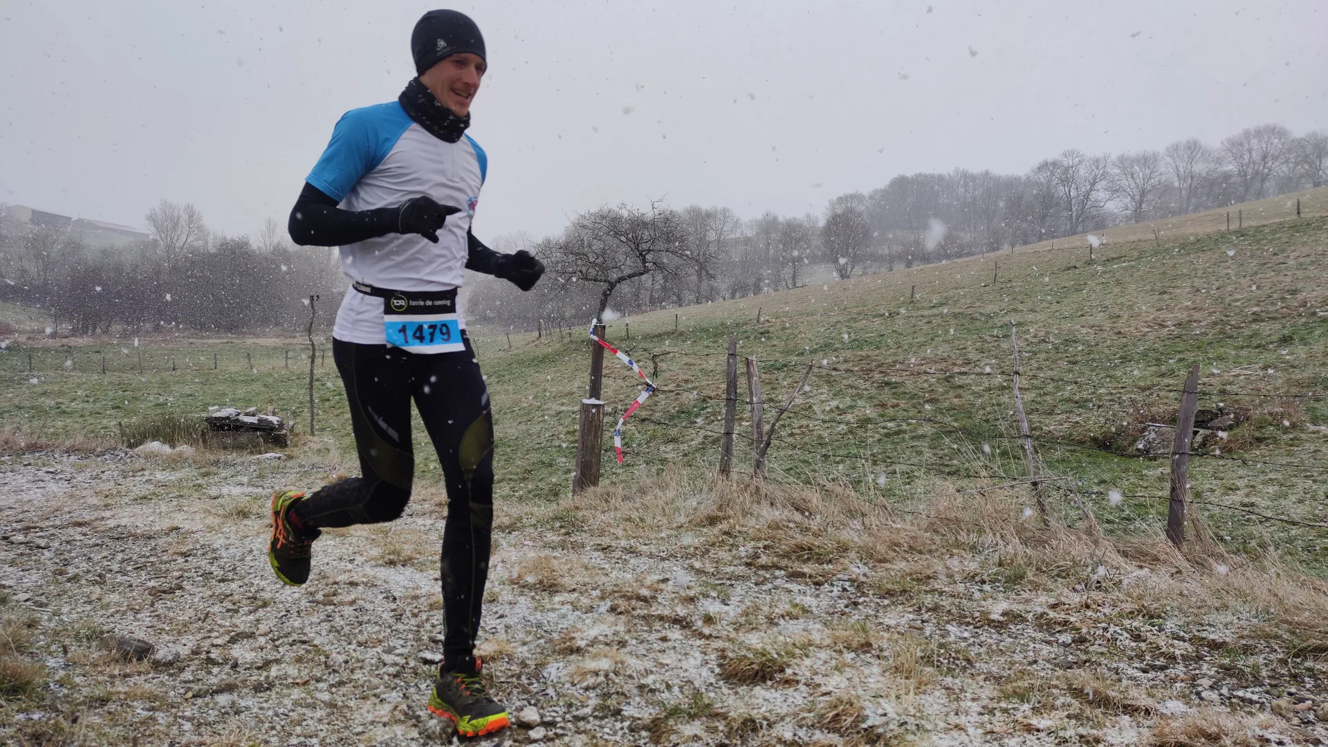 This image features a runner participating in a race during cold, wintry conditions.