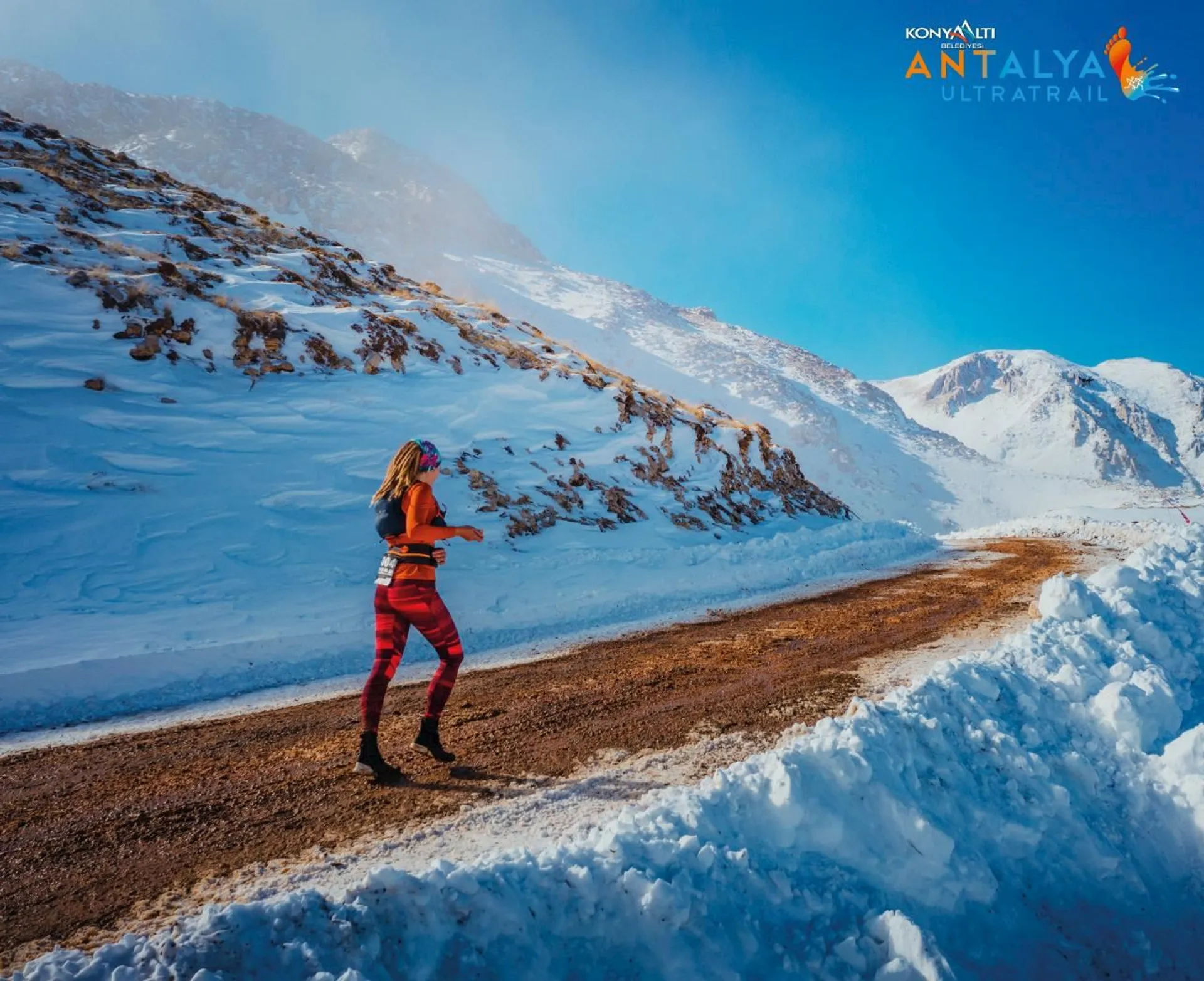 The image shows a person running on a cleared path through a snowy landscape. The