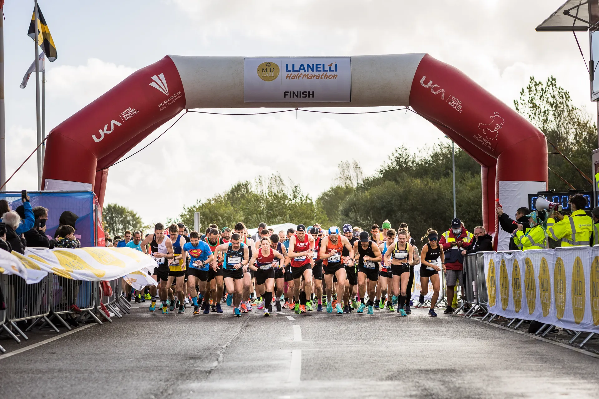 The image shows a group of runners at the starting line of the Llanelli