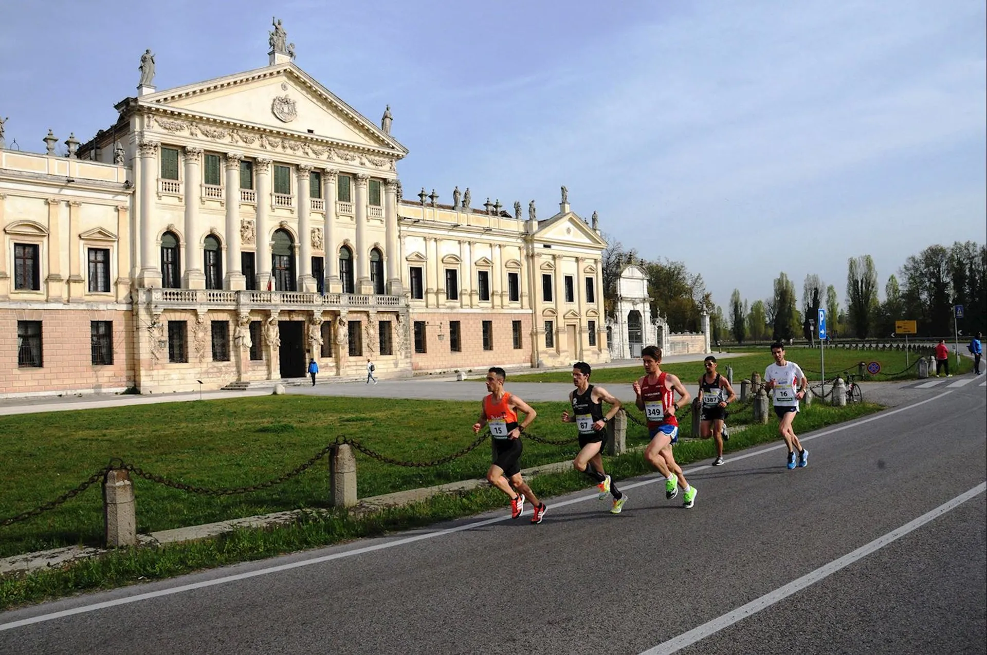 The image shows a group of runners in a race on a paved road. They