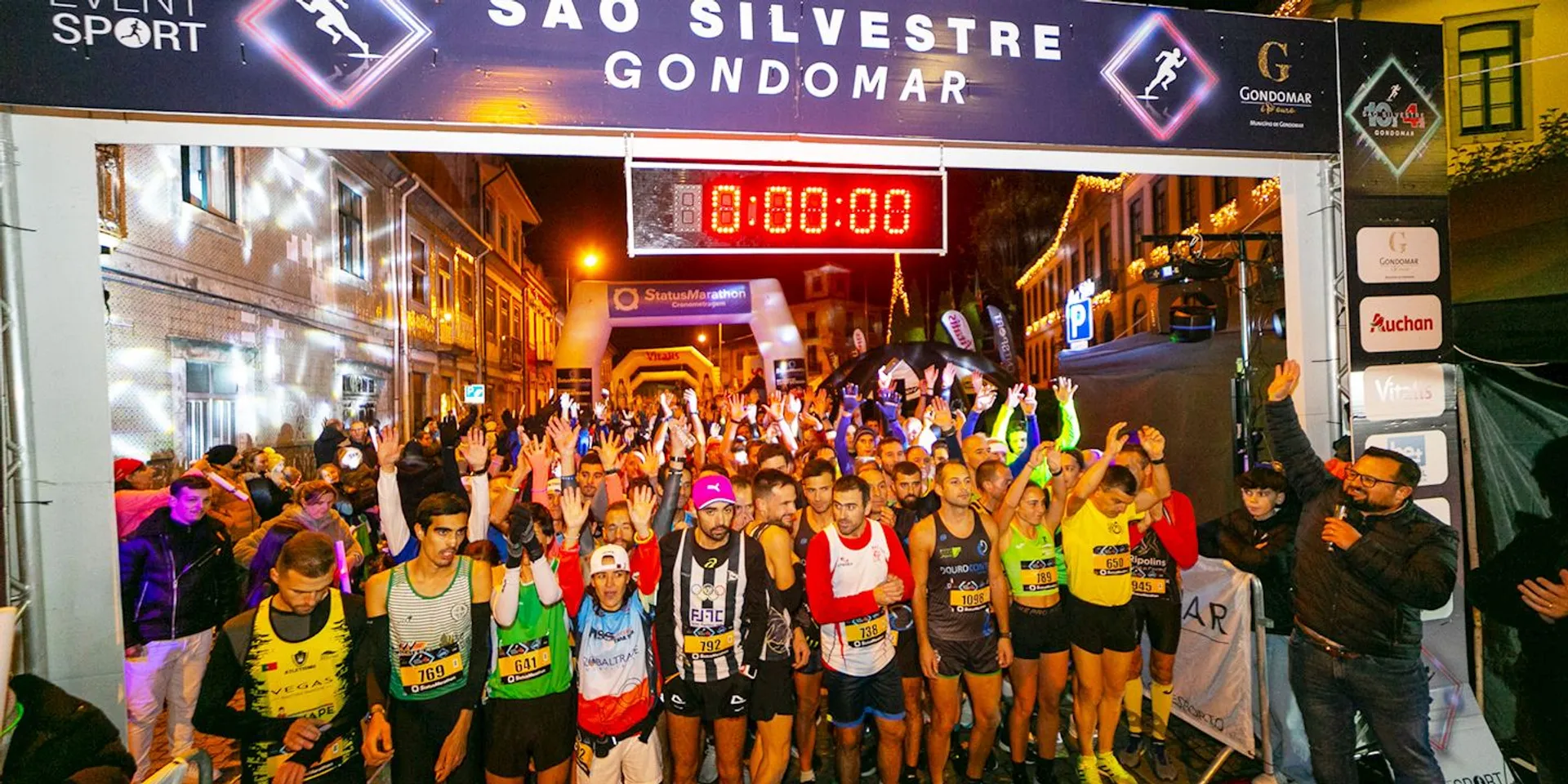 This image shows a nighttime scene of a road running event. A large group of