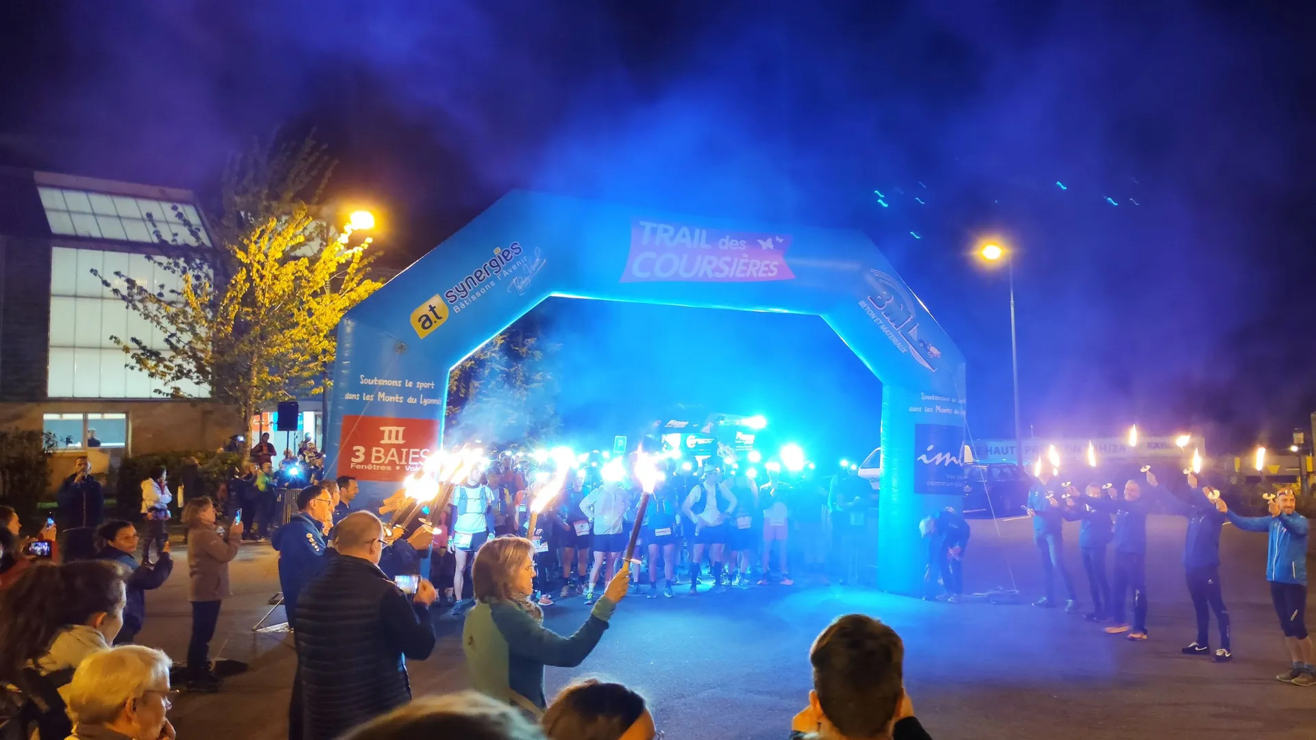 The image depicts a night-time event with several people gathered around an inflatable archway