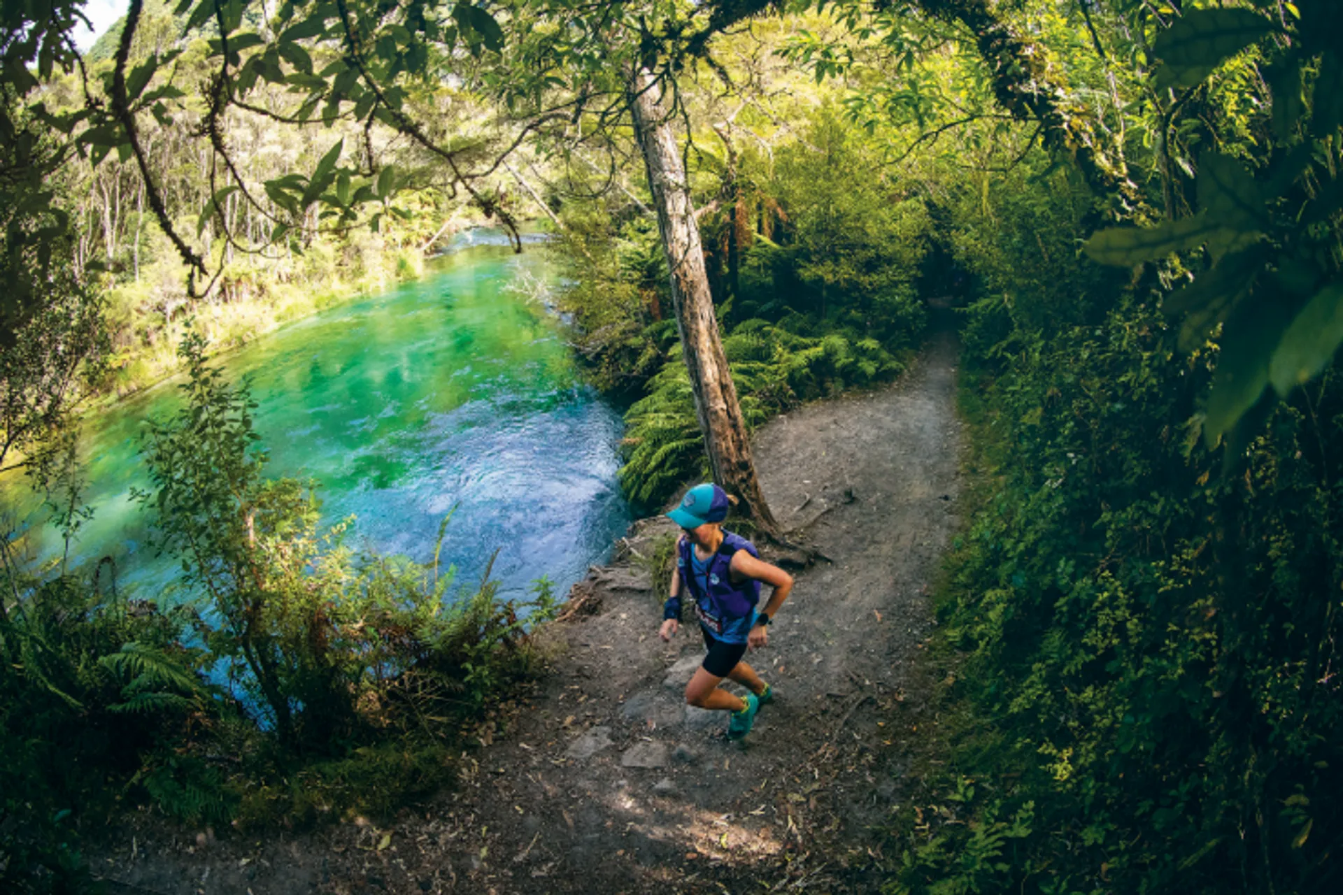The image shows a person jogging on a trail through a beautiful natural landscape. The