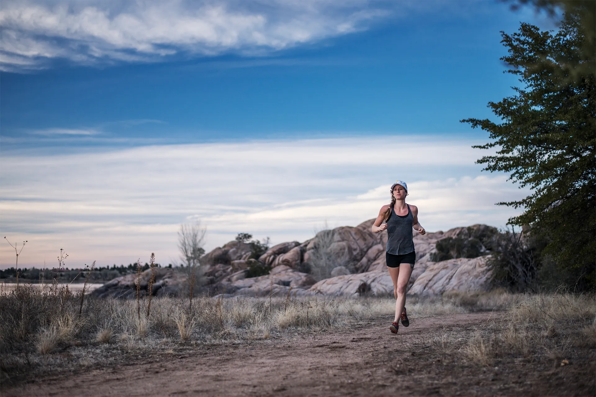 The image depicts a person jogging along a dirt path in a natural, outdoor setting