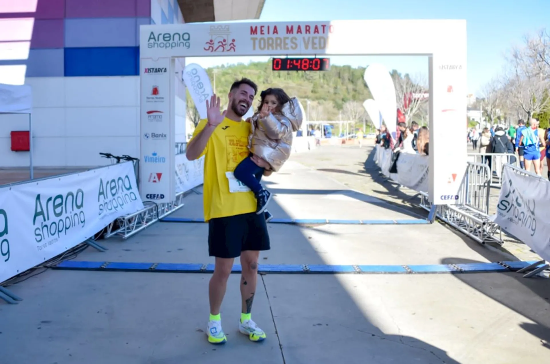 The image shows a joyful moment at the finish line of a half marathon race,