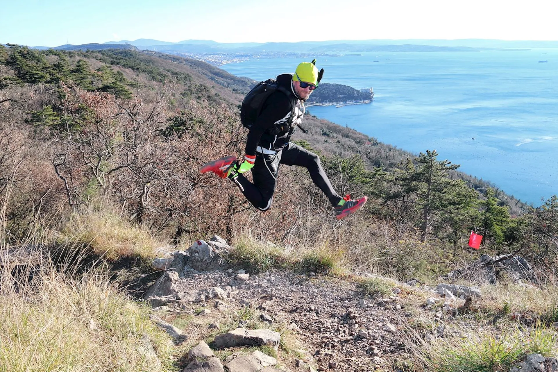 The image depicts a person engaged in trail running. They are captured in mid-air