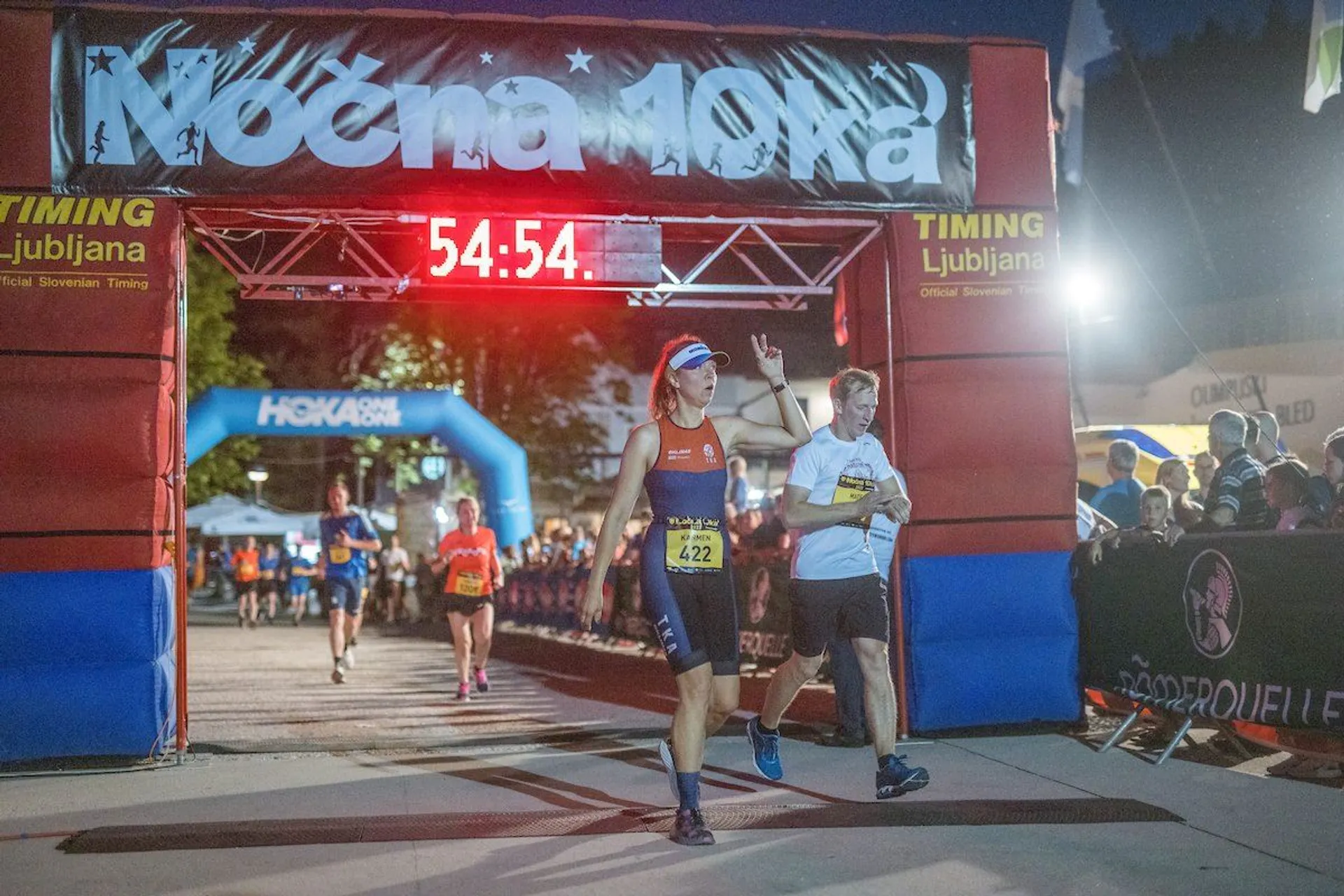 In this image, we see a nighttime athletic event with a participant crossing the finish