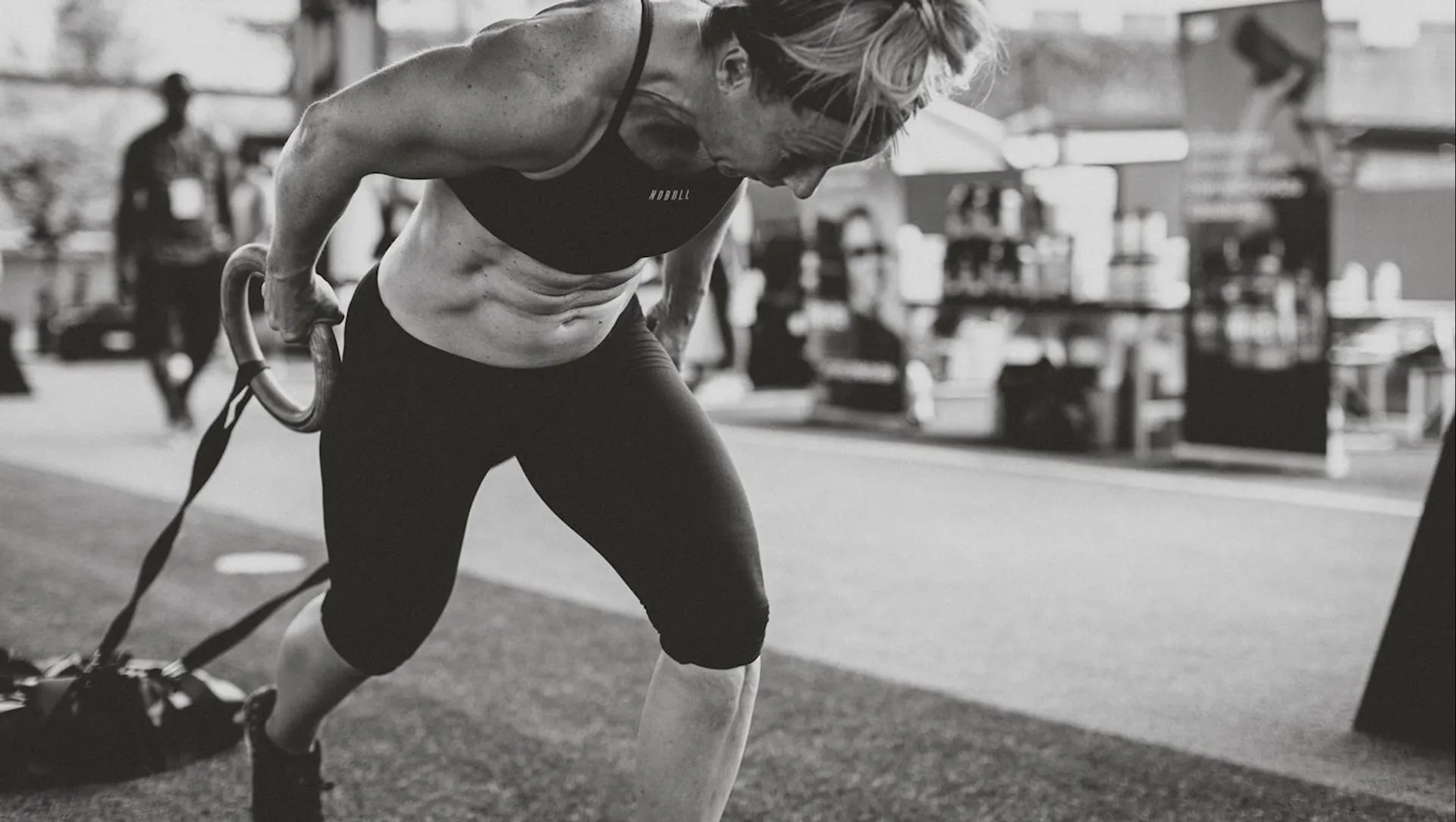 The image depicts a person engaged in a physical workout. The individual is pulling on