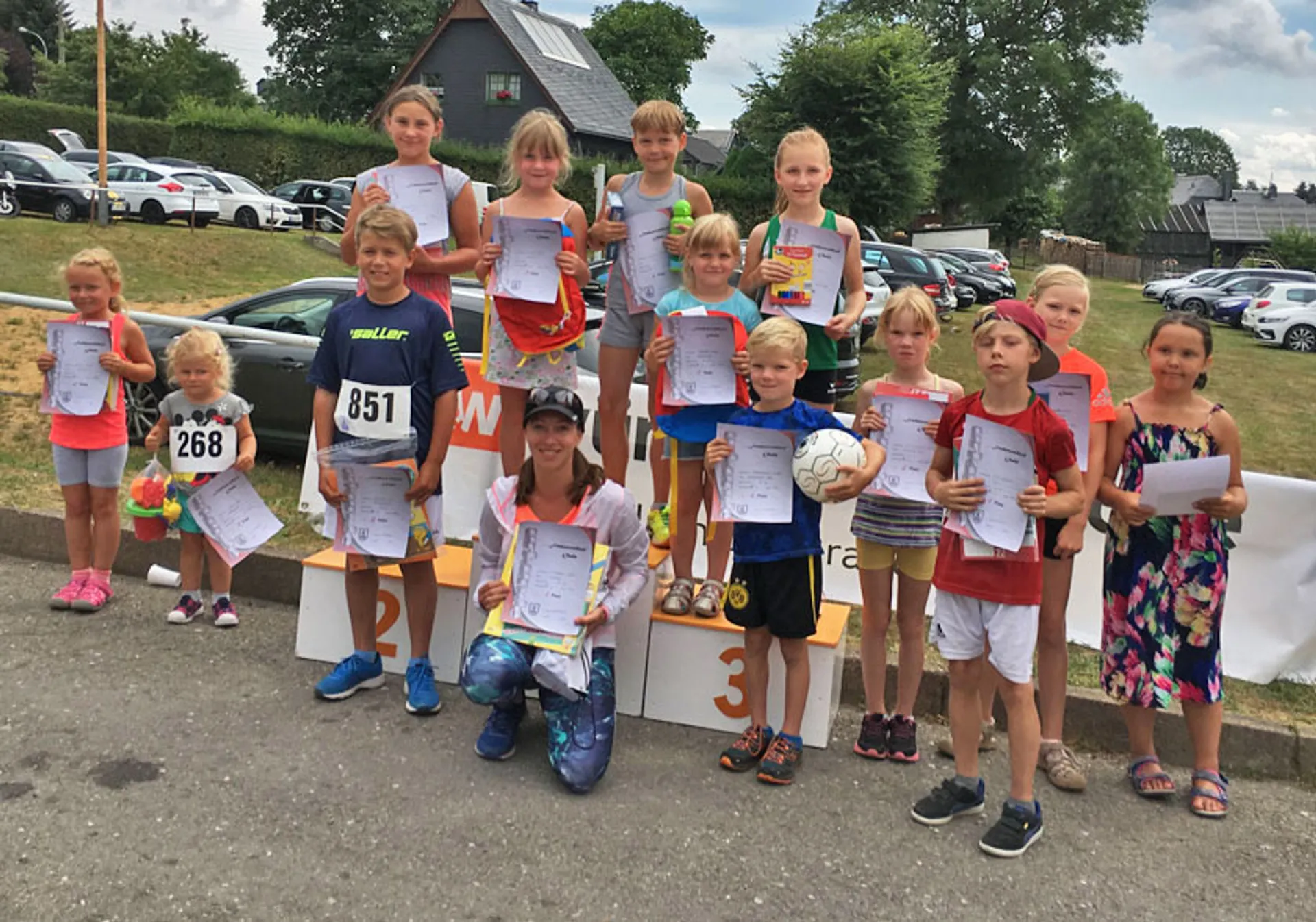 The image shows a group of children with a couple of adults, gathered for what