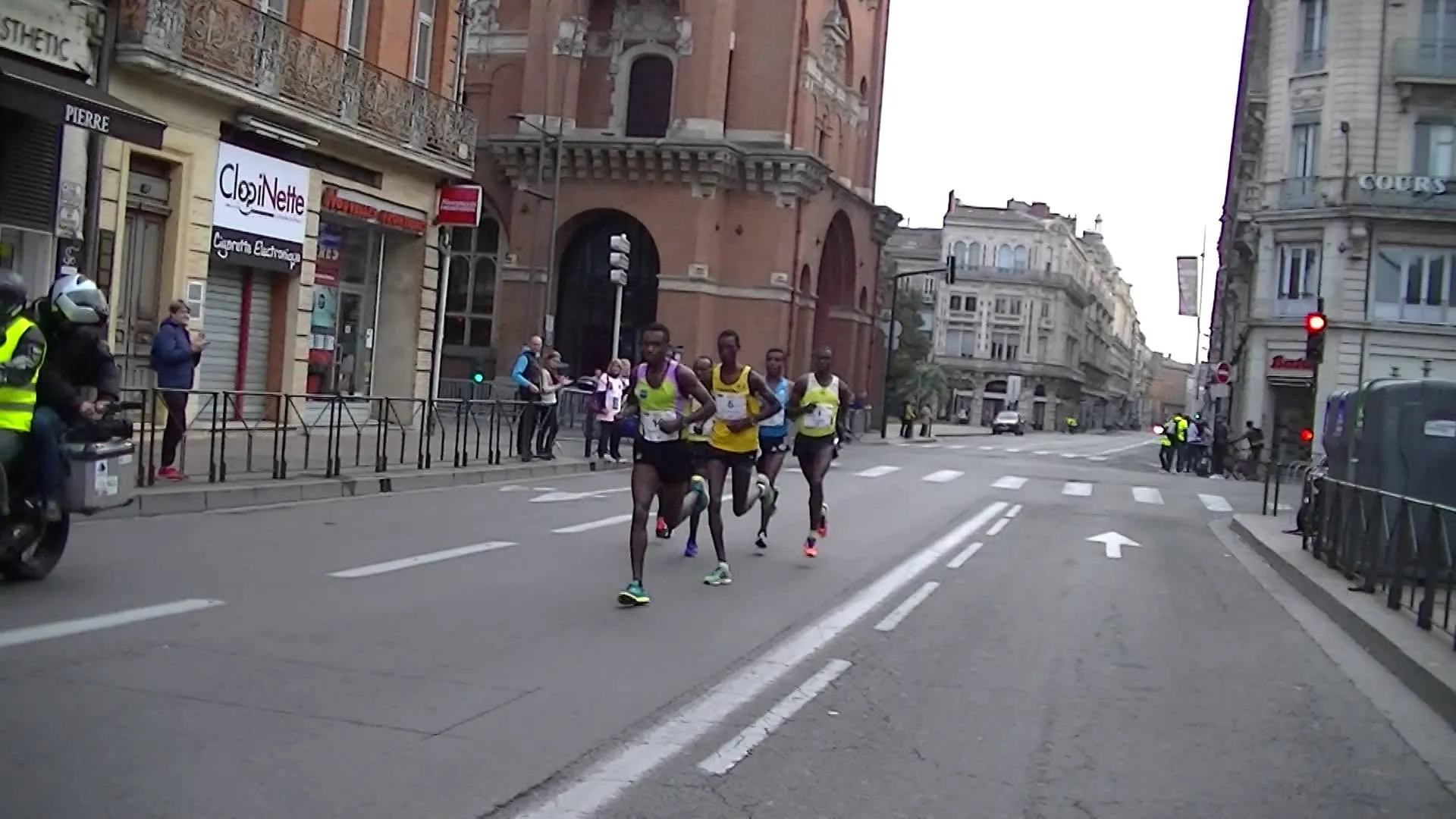 This image shows a group of runners leading a road race, with spectators visible on