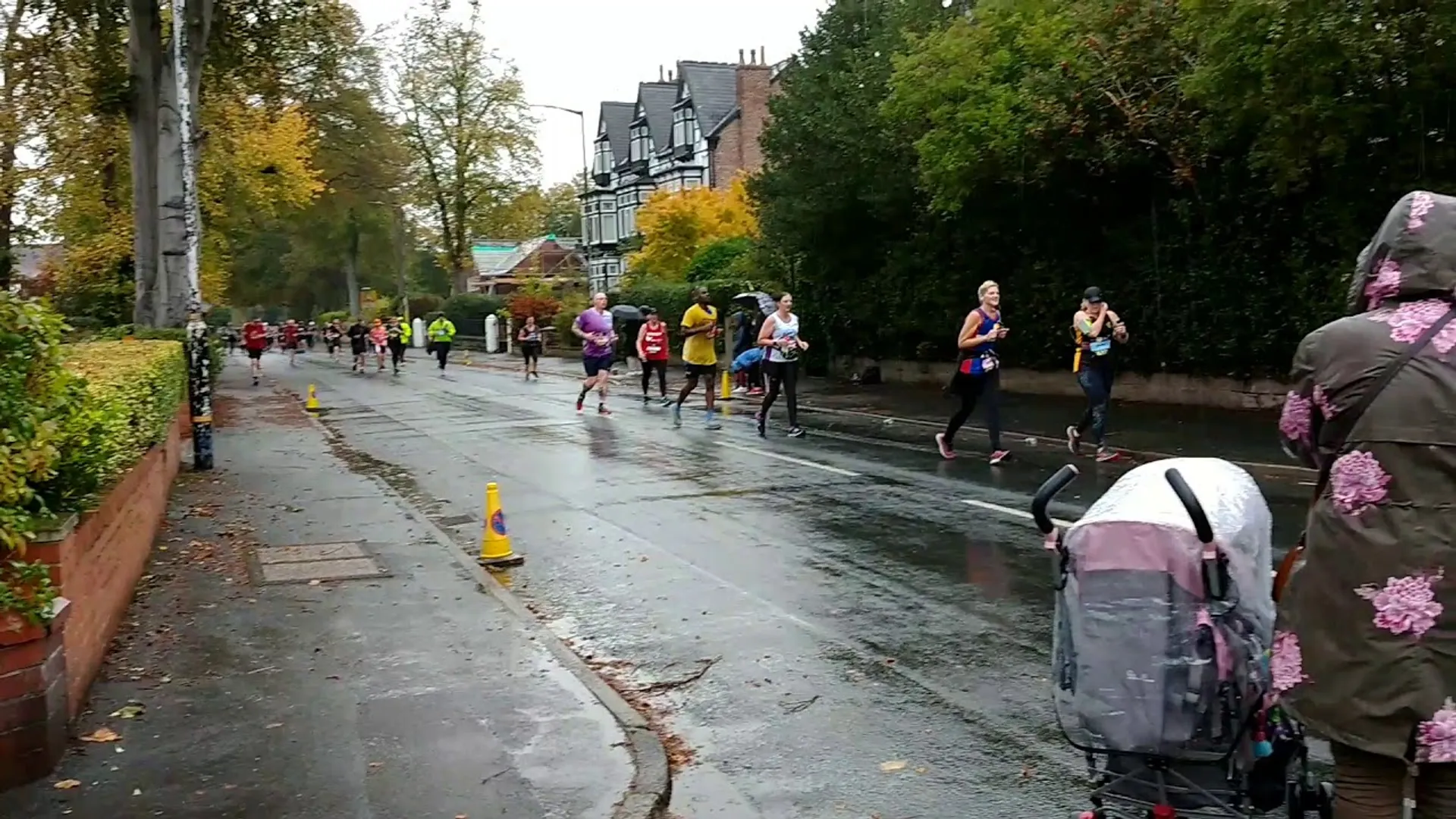 This image shows a street scene of a running event on a wet day. Run