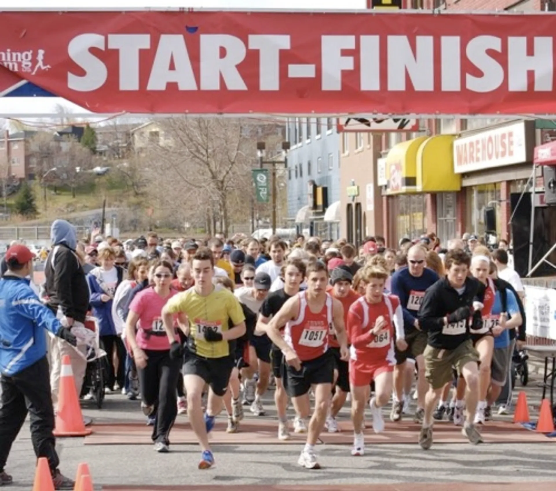 The image shows a group of runners at the start of a race. They are