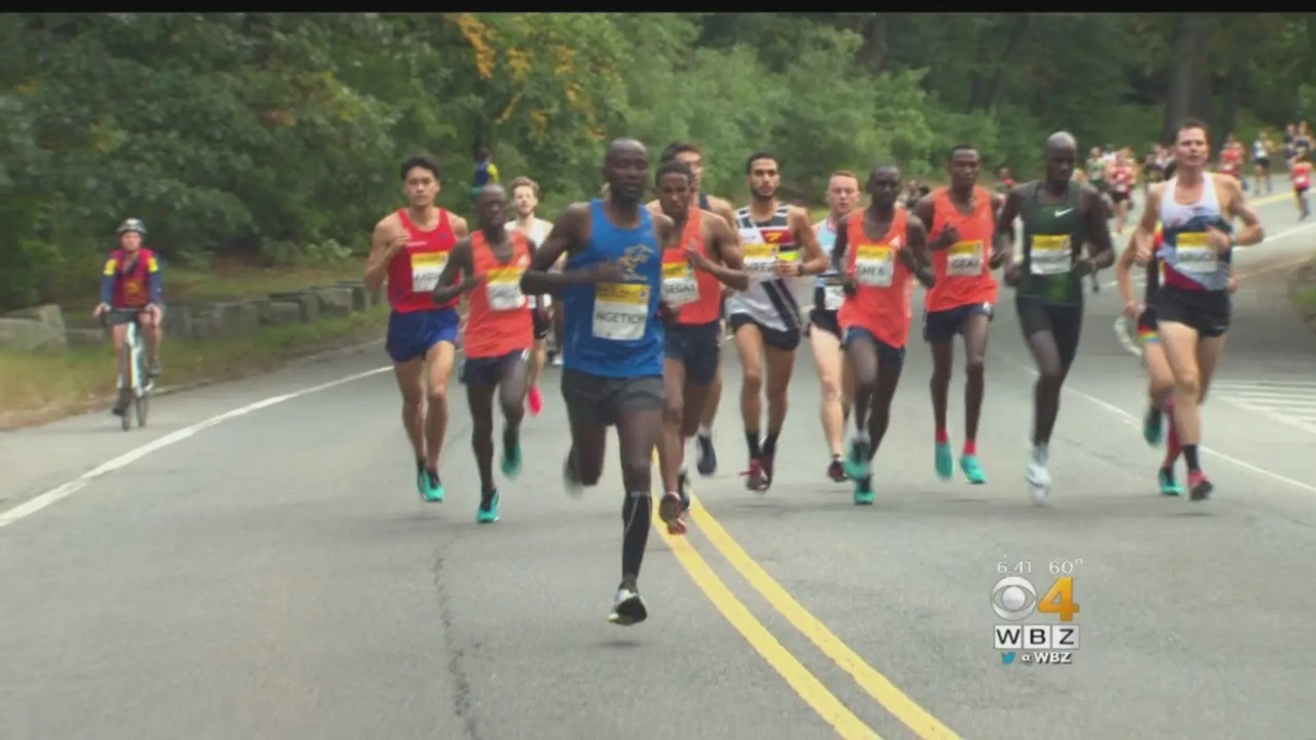 The image shows a group of runners participating in a road race. They appear to