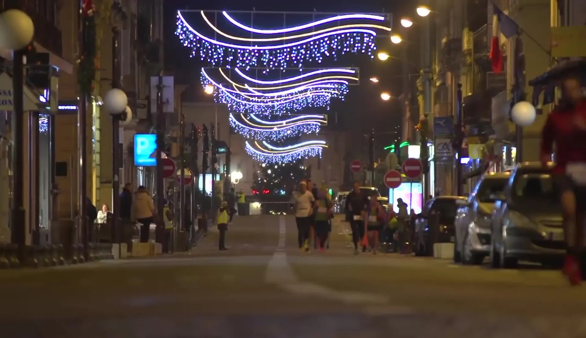 The image depicts a city street at night adorned with decorative lights, possibly for a