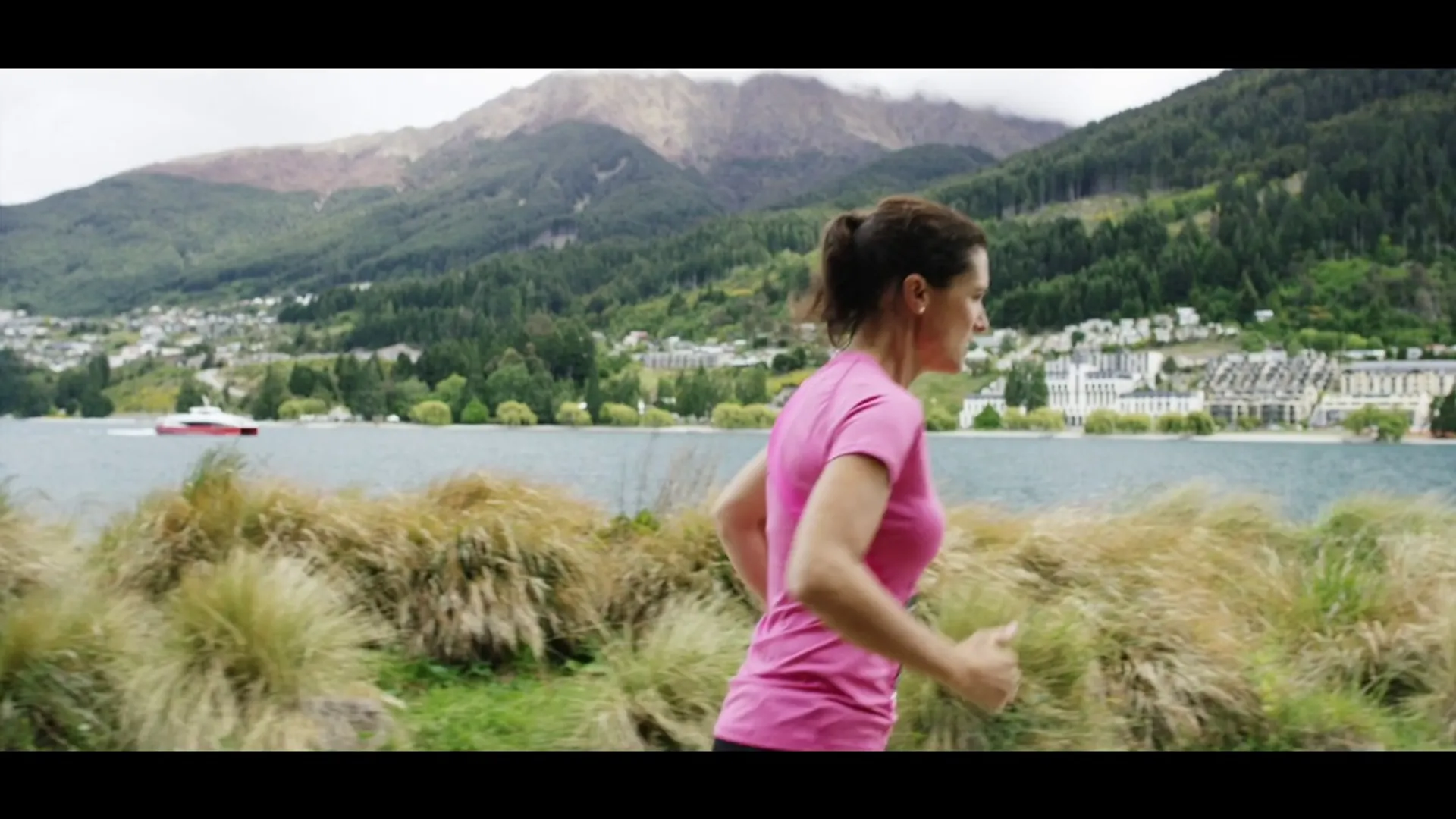 The image depicts a woman jogging. She is wearing a pink top and appears to