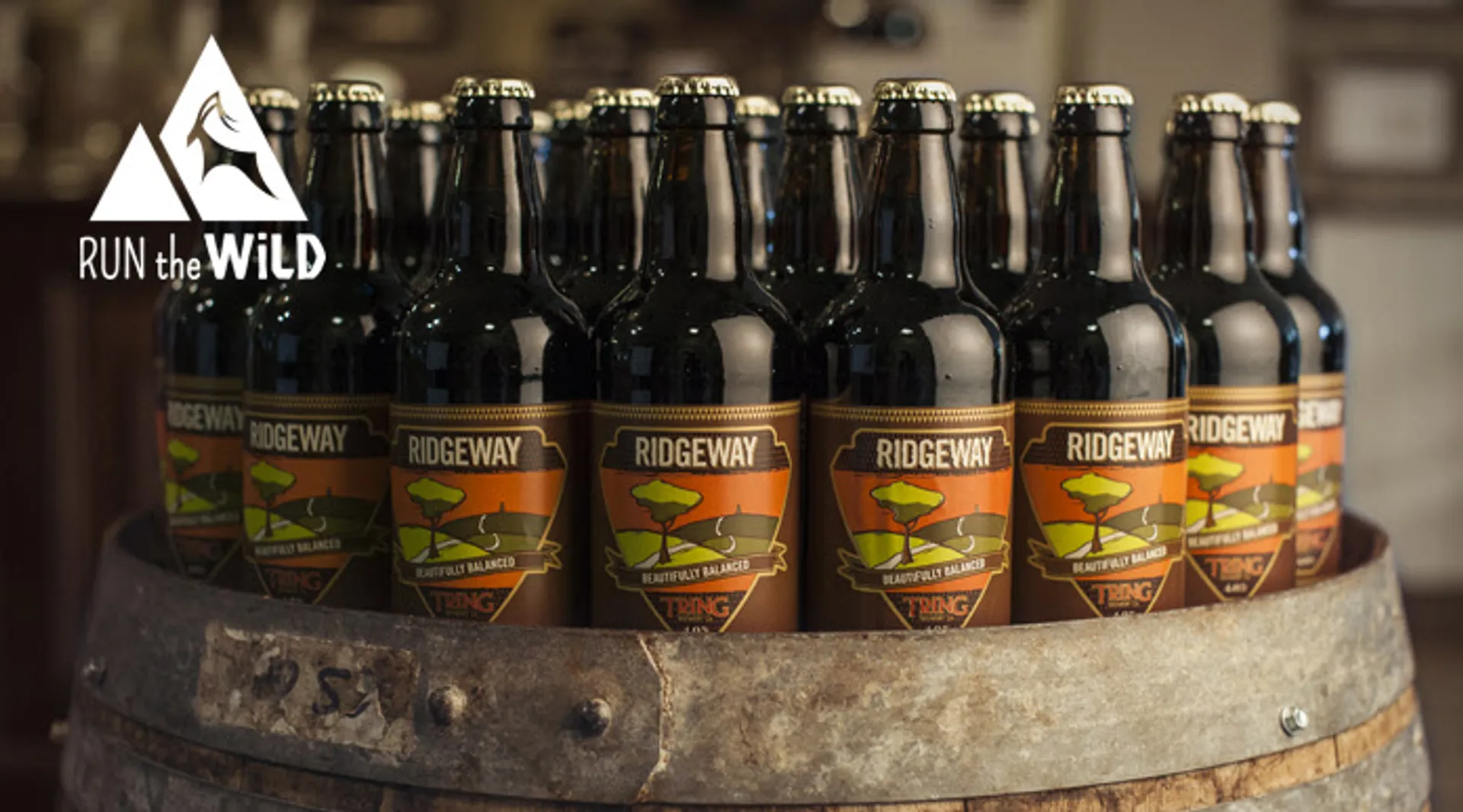 The image shows a collection of beer bottles placed on a wooden barrel. The labels