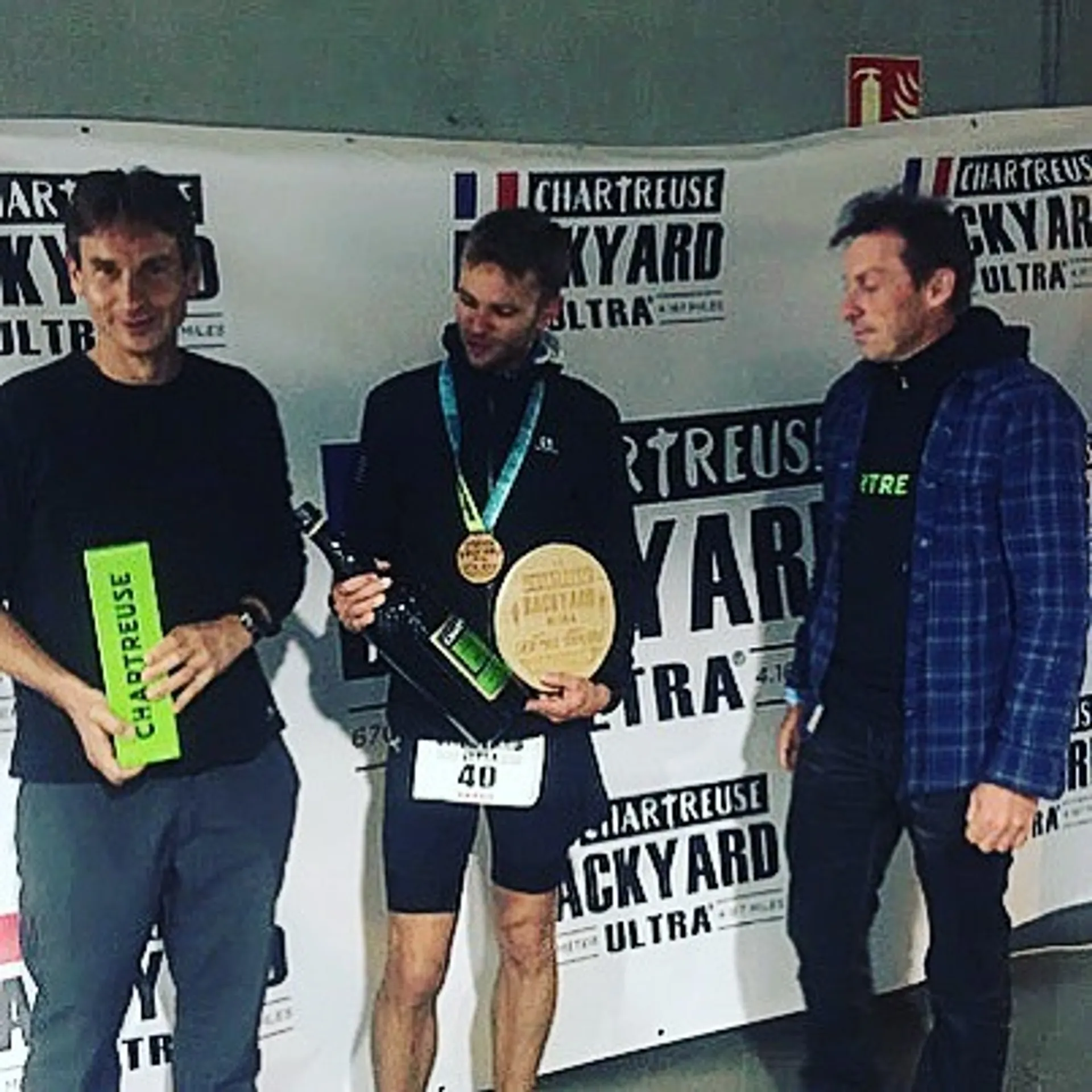 The image features three individuals standing in front of a backdrop that has the text "