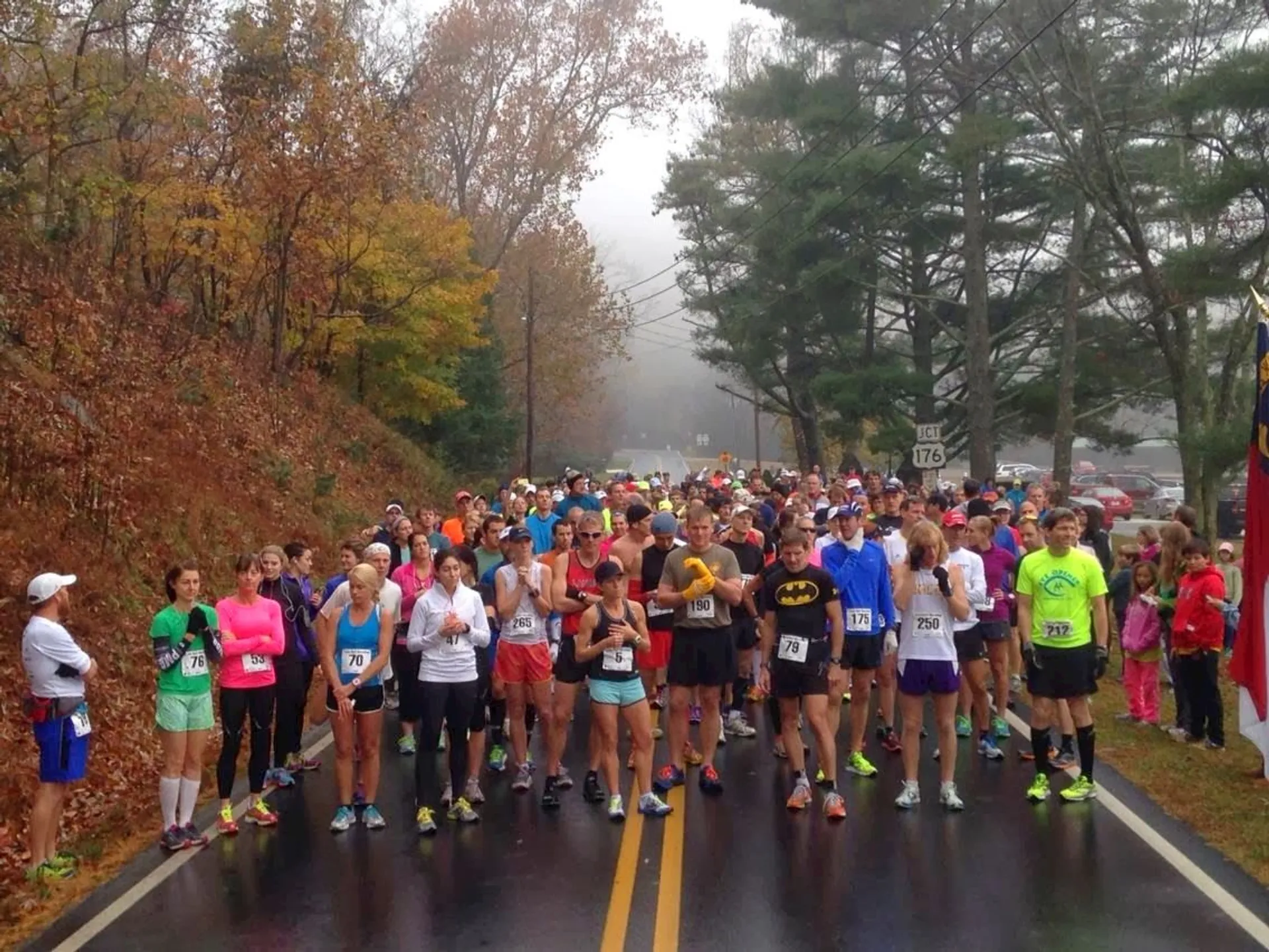 The image depicts a group of runners lined up on a road, ready to start