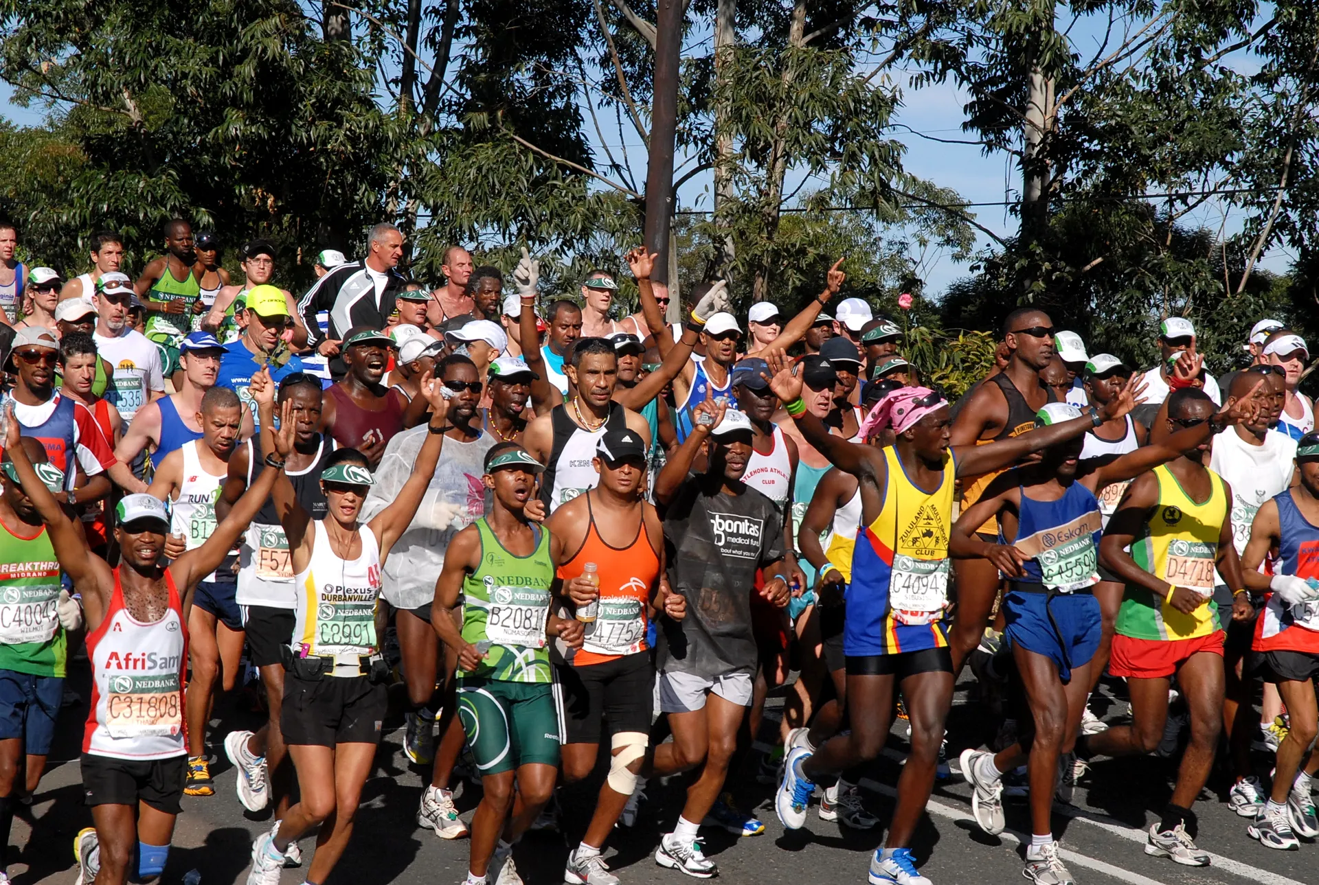The image shows a large group of runners participating in a road race. Most of